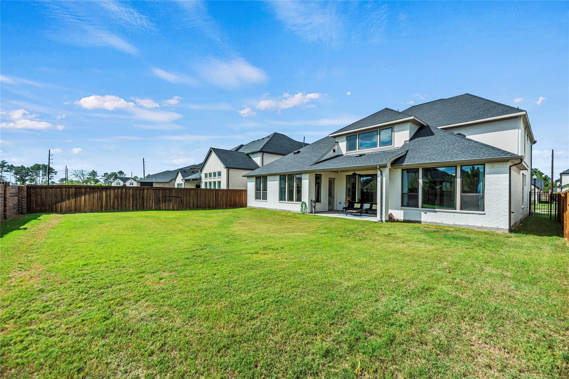4810 Antler Run Drive, Spring, TX 77386 Expansive backyard with lush green lawn, perfect for outdoor activities, featuring a modern two-story home with a spacious covered patio ideal for relaxation and entertainment.