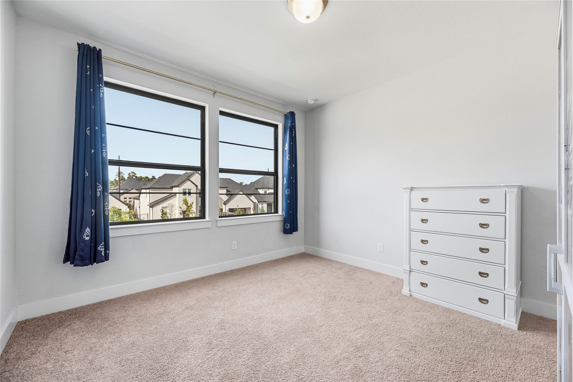 4810 Antler Run Drive, Spring, TX 77386 Airy bedroom featuring large windows with elegant navy curtains, neutral carpeting, and a classic white dresser.