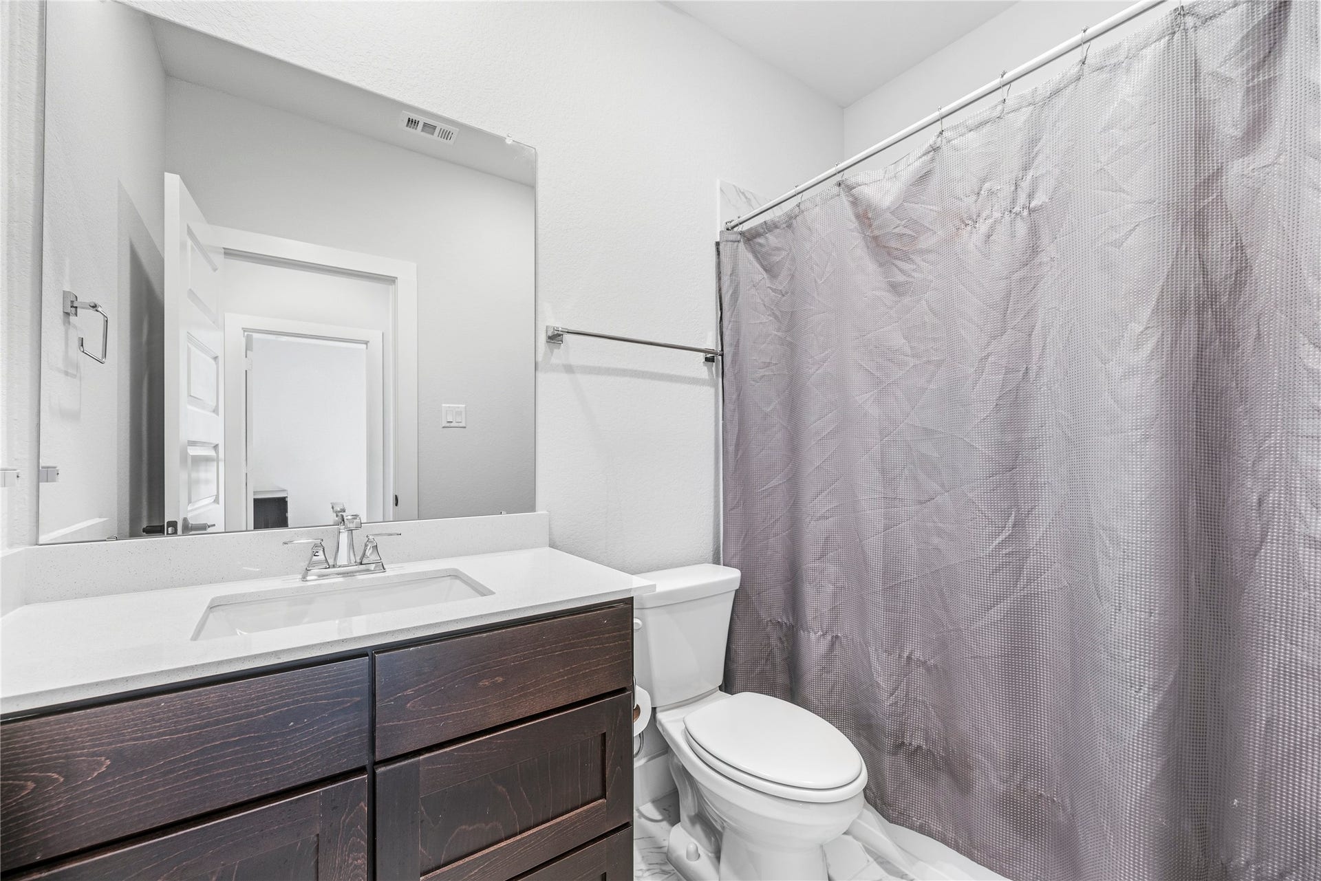 4810 Antler Run Drive, Spring, TX 77386 Bright bathroom featuring a sleek vanity with dark wood cabinetry, a modern sink, and a shower with a neutral-toned curtain.