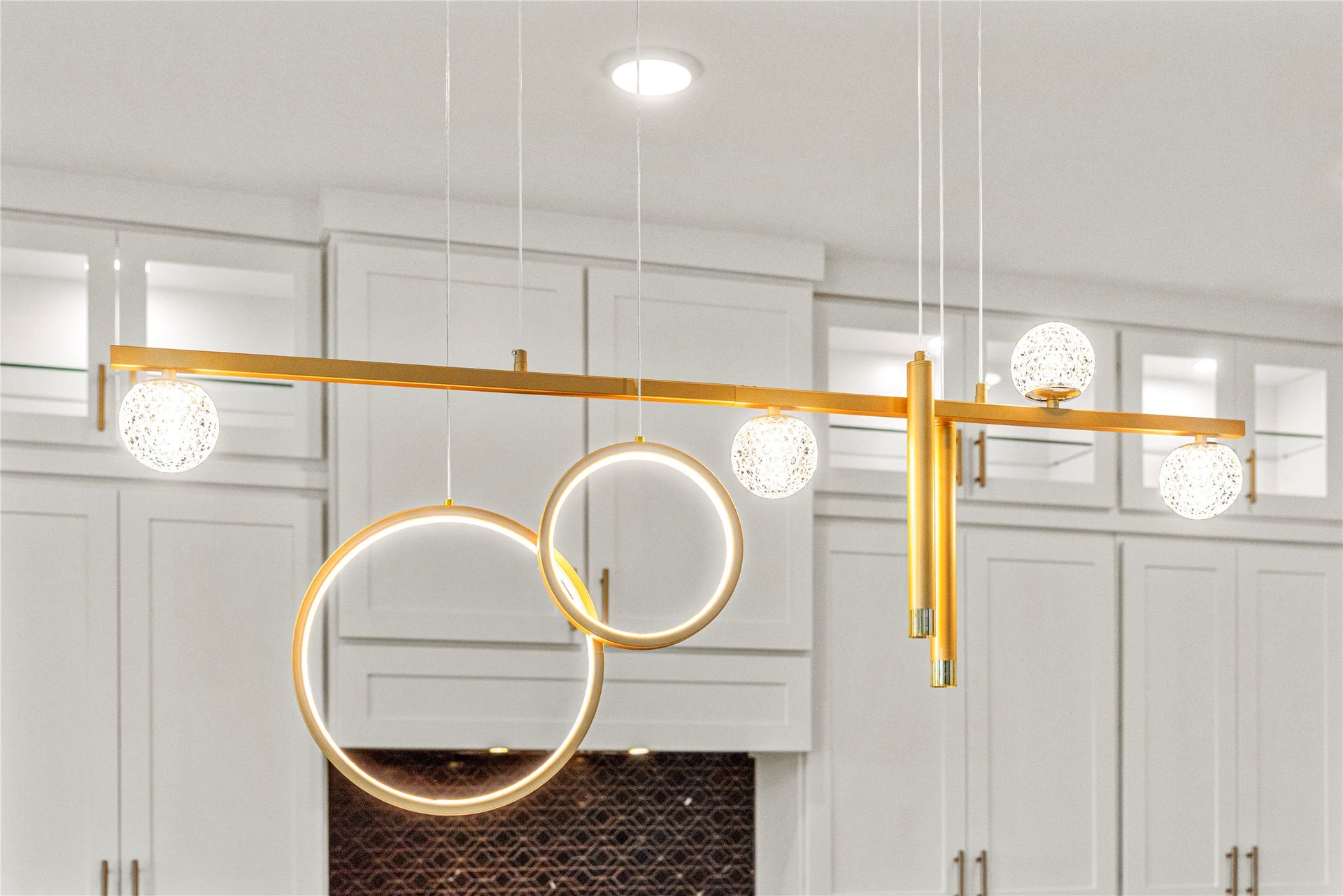 4810 Antler Run Drive, Spring, TX 77386 High-end chandelier with gold accents and unique circular design, perfectly complementing the elegant white cabinetry.