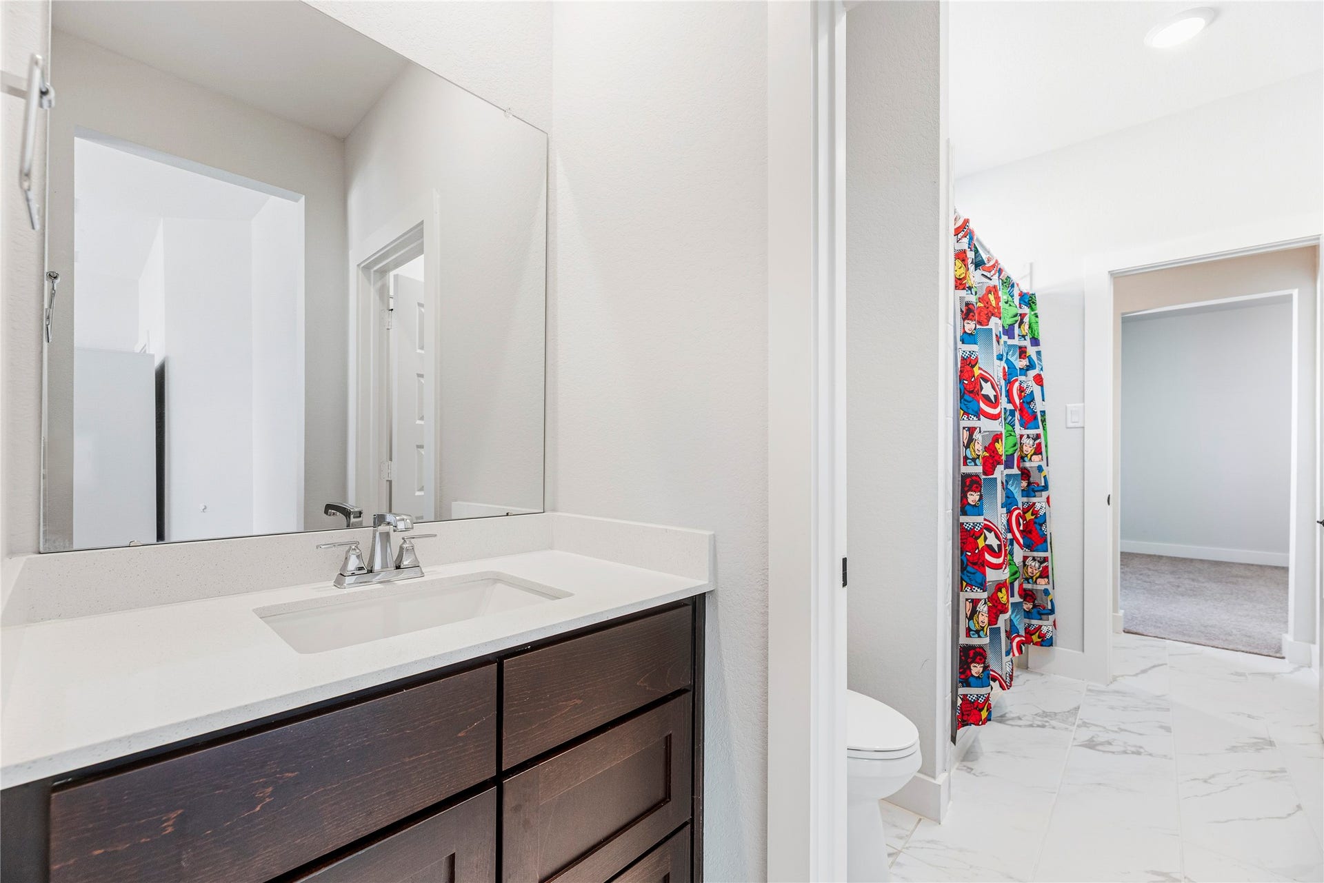 4810 Antler Run Drive, Spring, TX 77386 Jack and Jill bathroom featuring a sleek dark wood vanity with a modern sink and a playful, colorful shower curtain adding a touch of fun.