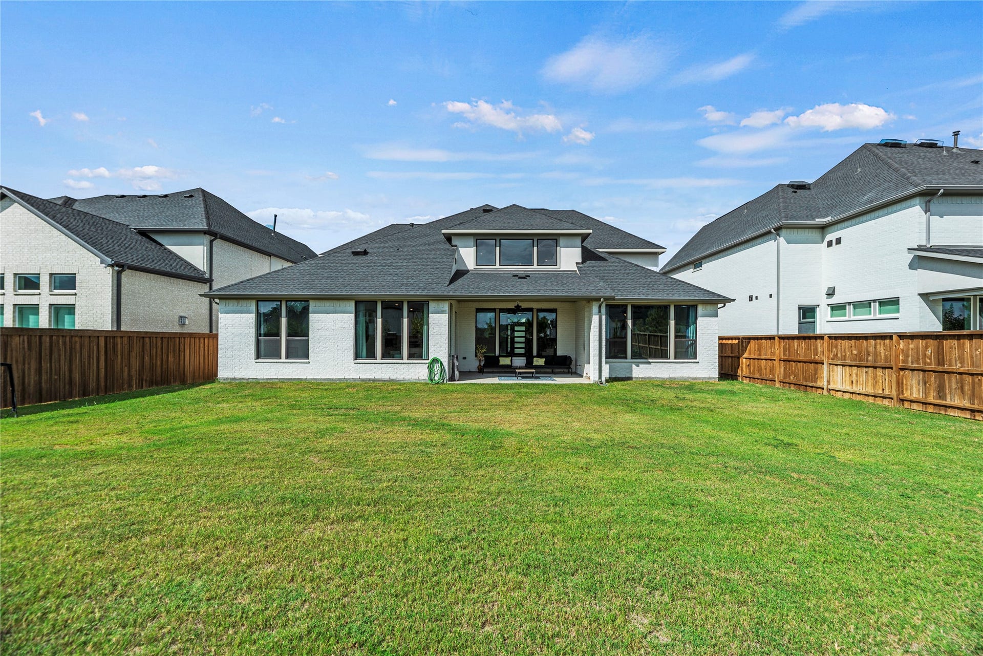 4810 Antler Run Drive, Spring, TX 77386 Spacious backyard with lush green lawn, perfect for outdoor activities, complemented by a modern two-story home featuring large windows and a covered patio.