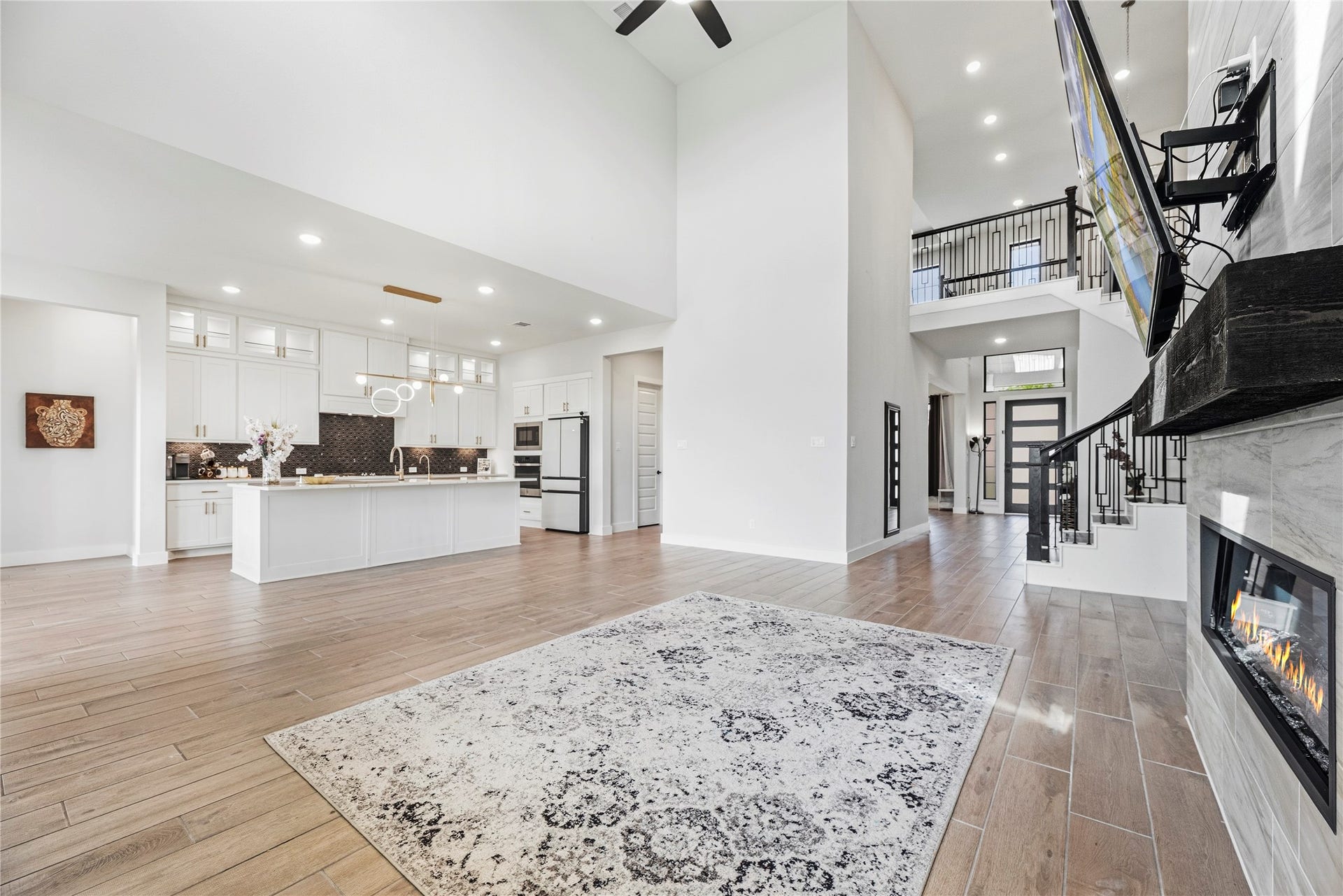 4810 Antler Run Drive, Spring, TX 77386 Stunning open-concept living area featuring high ceilings, a sleek modern kitchen with an island, a cozy fireplace, and elegant hardwood floors, perfect for entertaining and relaxation.
