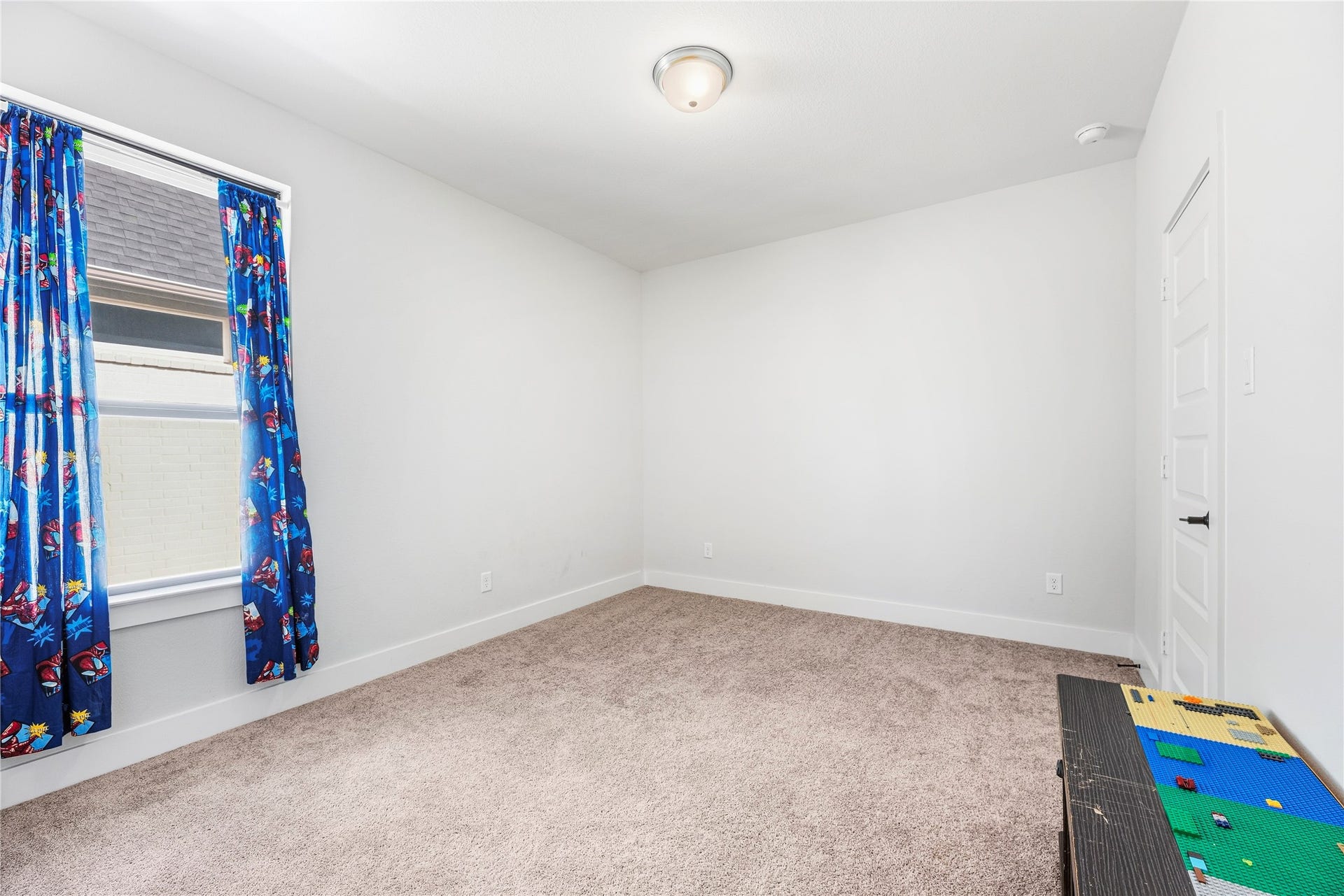 4810 Antler Run Drive, Spring, TX 77386 Bright and cozy bedroom with plush carpeting, featuring a window dressed with colorful curtains that add a playful touch.