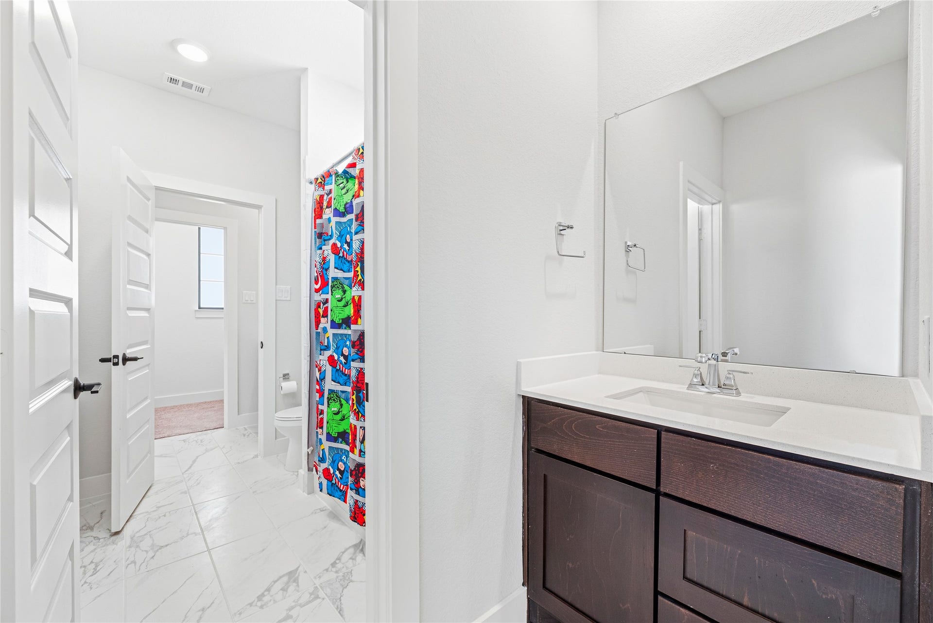 4810 Antler Run Drive, Spring, TX 77386 Bright bathroom featuring marble tile flooring, a modern vanity with a sleek countertop, and a vibrant shower curtain adding a playful touch.