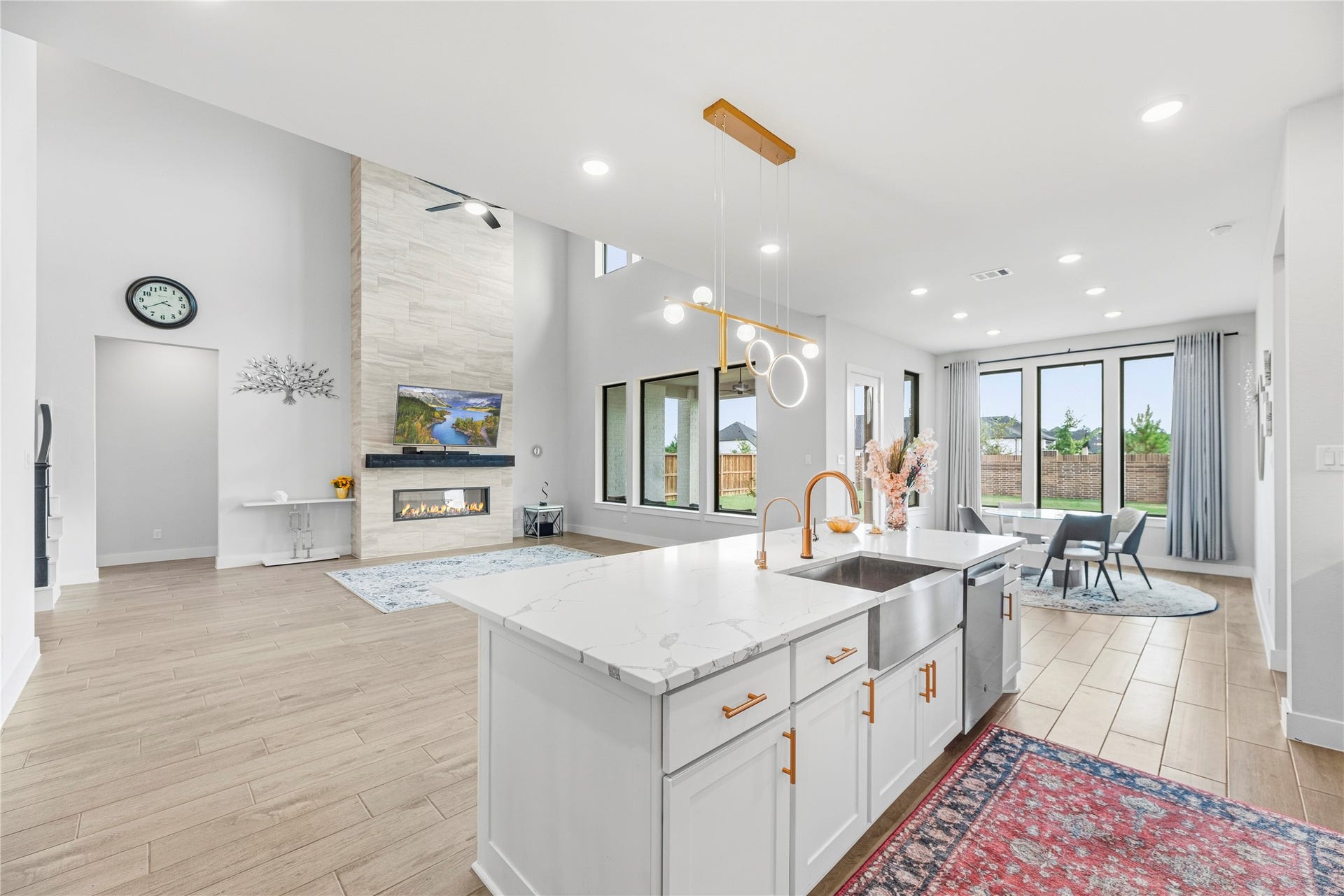 4810 Antler Run Drive, Spring, TX 77386 Bright and spacious open-concept living area featuring a modern kitchen with a large island, elegant pendant lighting, and a cozy fireplace. Expansive windows provide abundant natural light and views of the backyard, perfect for entertaining.