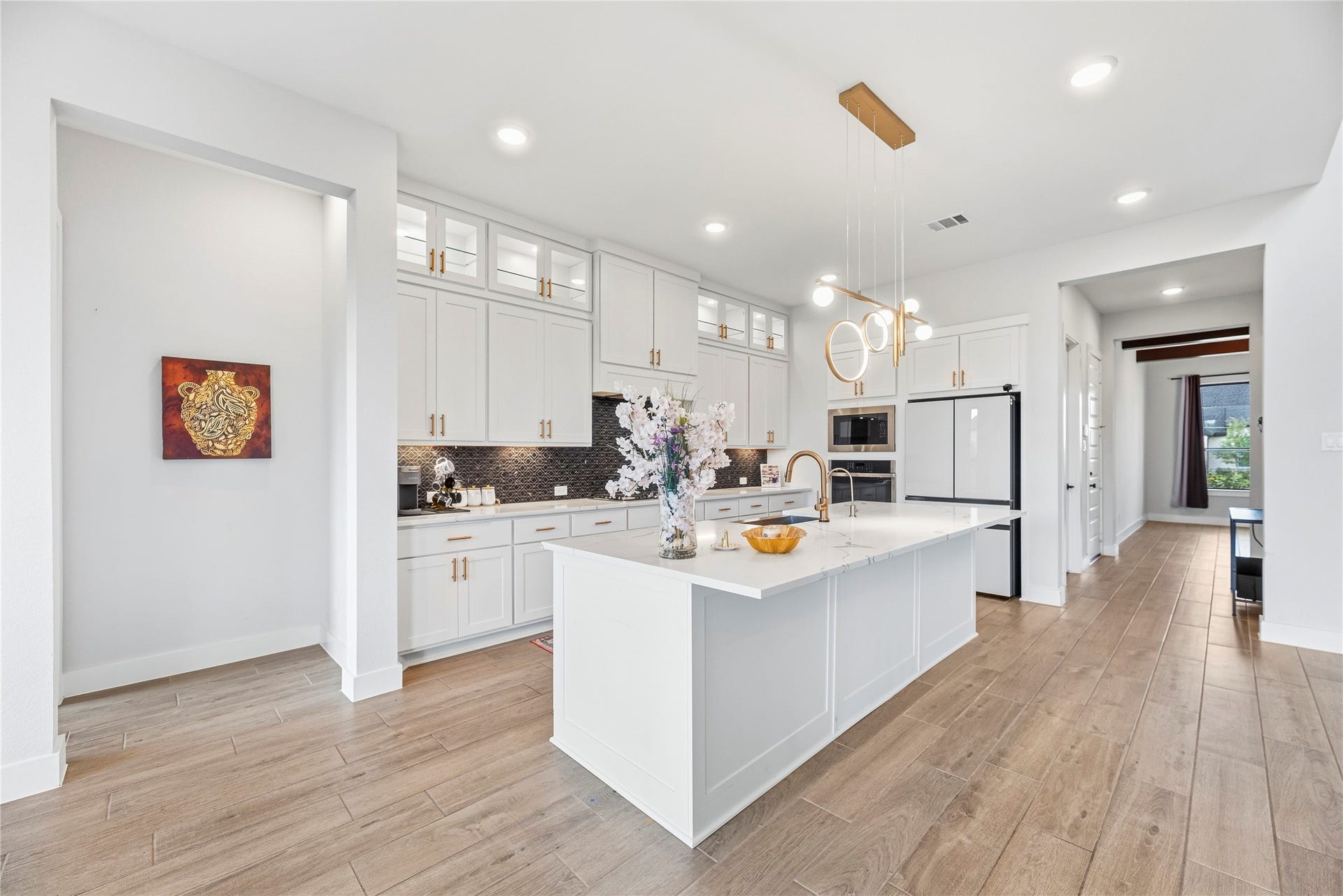 4810 Antler Run Drive, Spring, TX 77386 Stunning modern kitchen with elegant white cabinetry, a spacious island with a sleek waterfall countertop, and stylish pendant lighting.