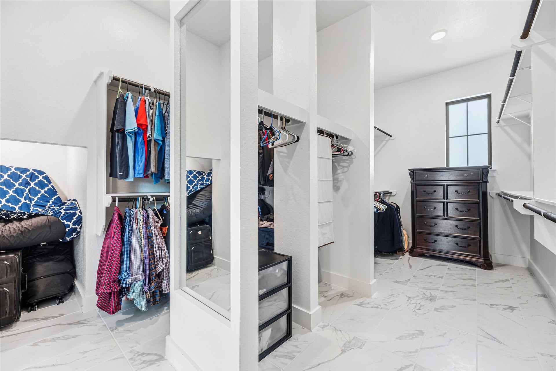 4810 Antler Run Drive, Spring, TX 77386 Spacious walk-in closet featuring elegant marble floors, ample hanging space, built-in shelving, and a dark wood dresser for stylish organization.