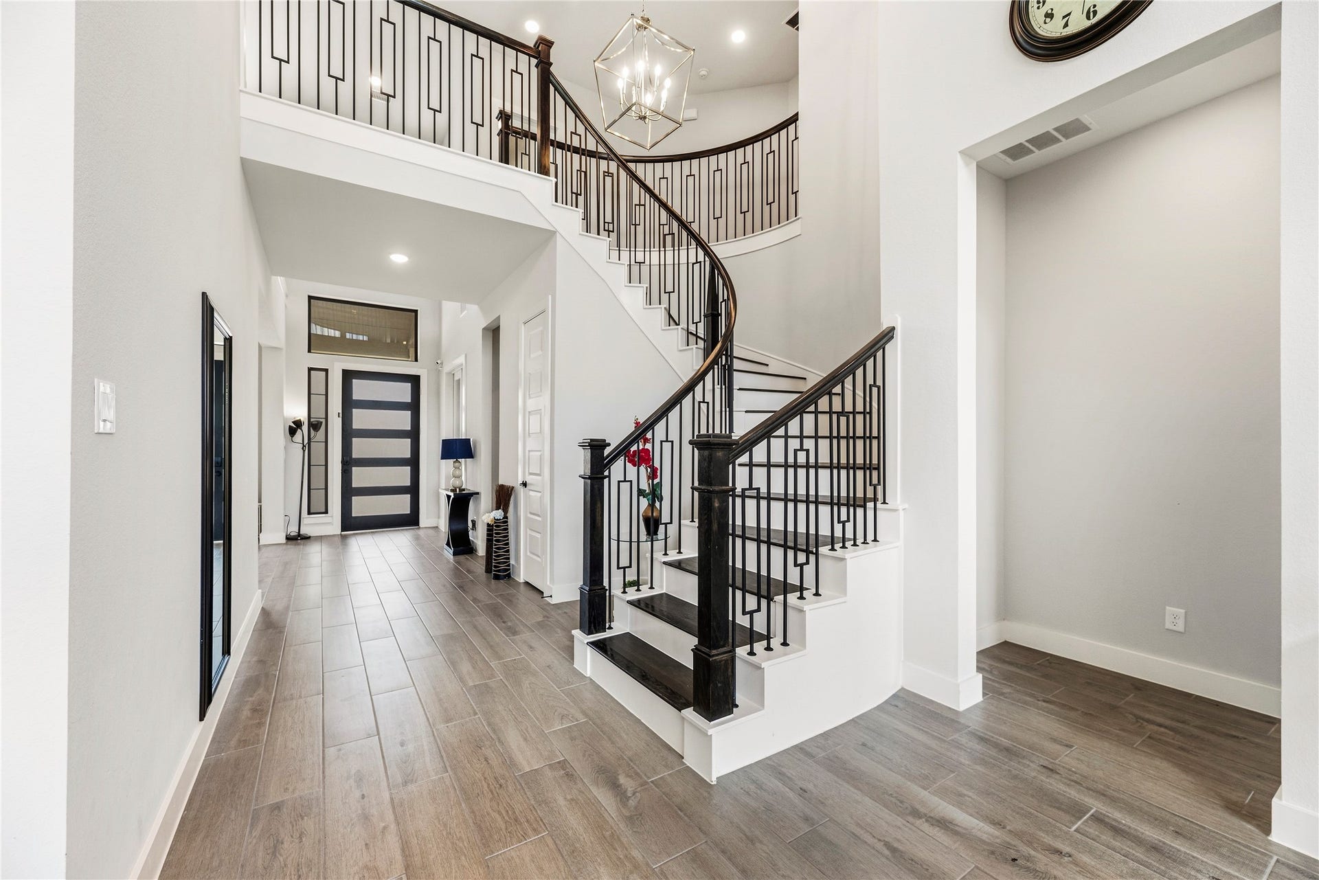 4810 Antler Run Drive, Spring, TX 77386 Elegant entryway with a striking, curved staircase featuring modern iron railings and rich wood accents, complemented by sleek tile flooring and a stylish front door.