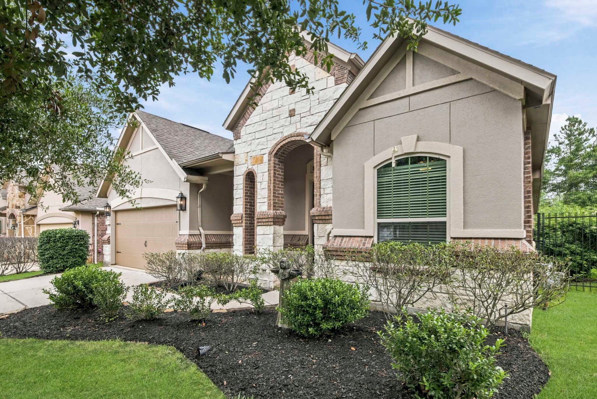11 Whispering Thicket Place, The Woodlands, TX 77375 Stunning home featuring stone/brick/stucco exterior, a welcoming archway entrance, and thoughtful landscaping that creates excellent curb appeal.