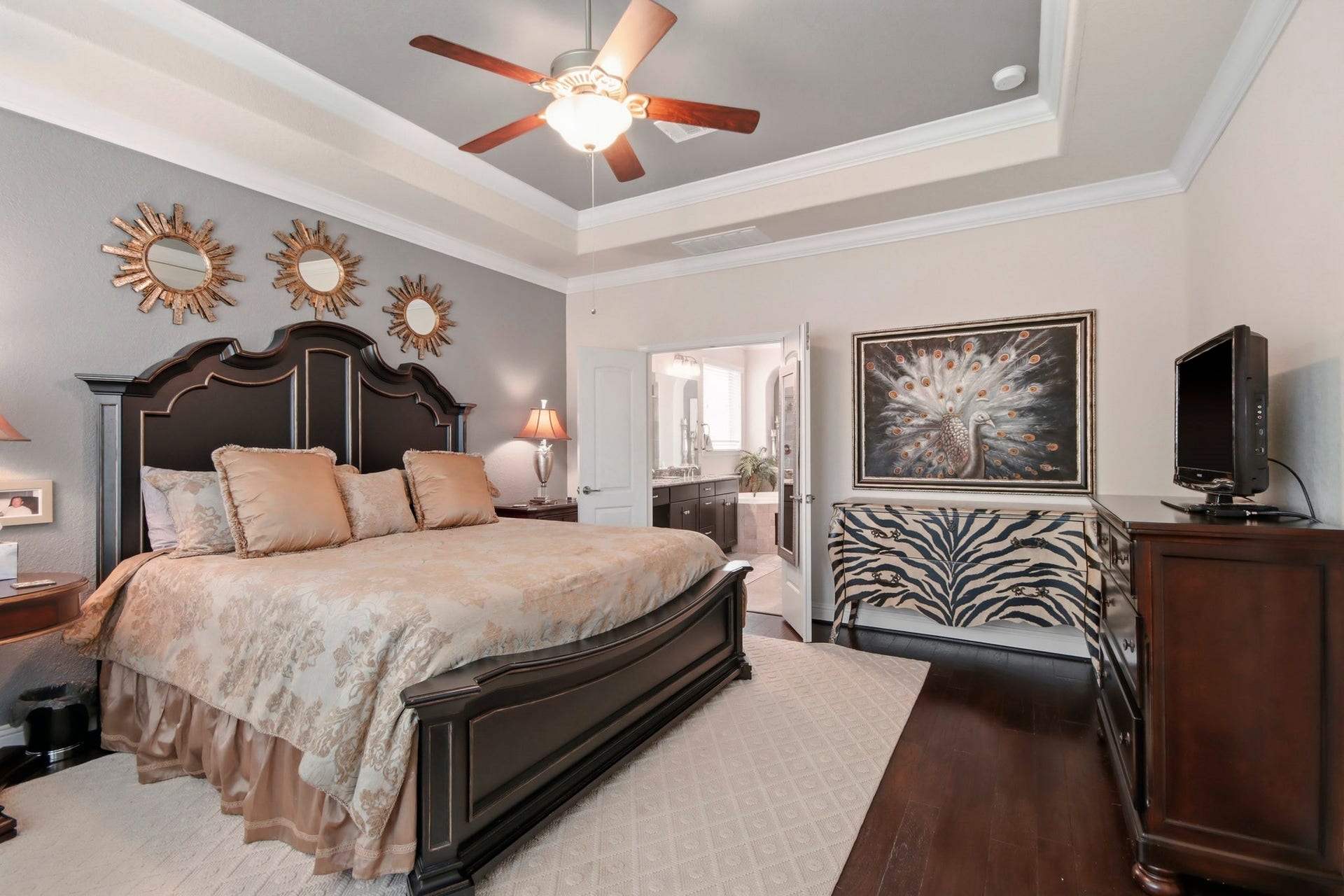 11 Whispering Thicket Place, The Woodlands, TX 77375 Inviting Primary Suite featuring a bay window and a ceiling fan with convenient access to an ensuite bathroom.