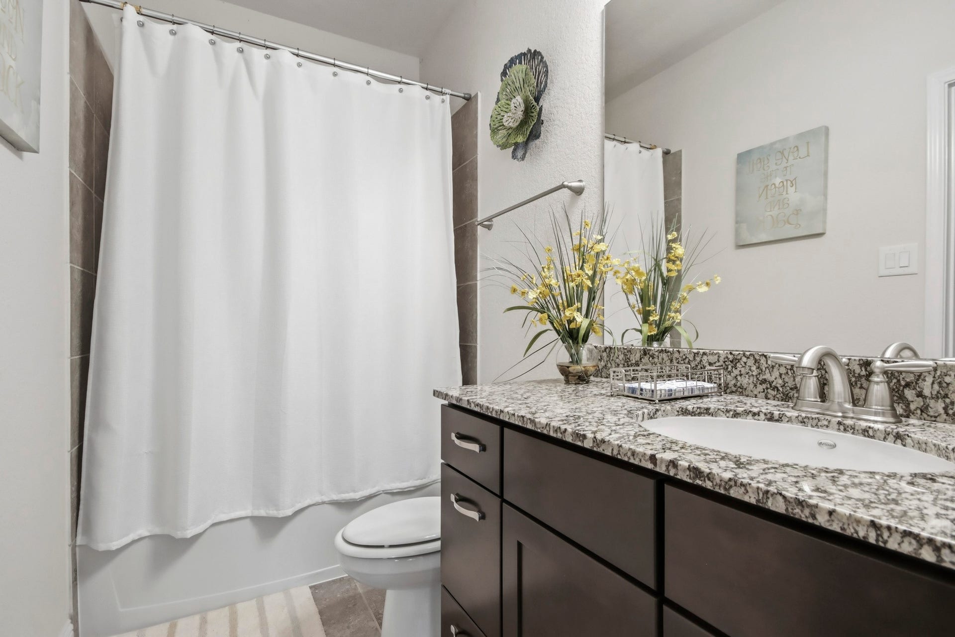 11 Whispering Thicket Place, The Woodlands, TX 77375 Guest bathroom featuring a sleek granite countertop and a stylish dark wood vanity.