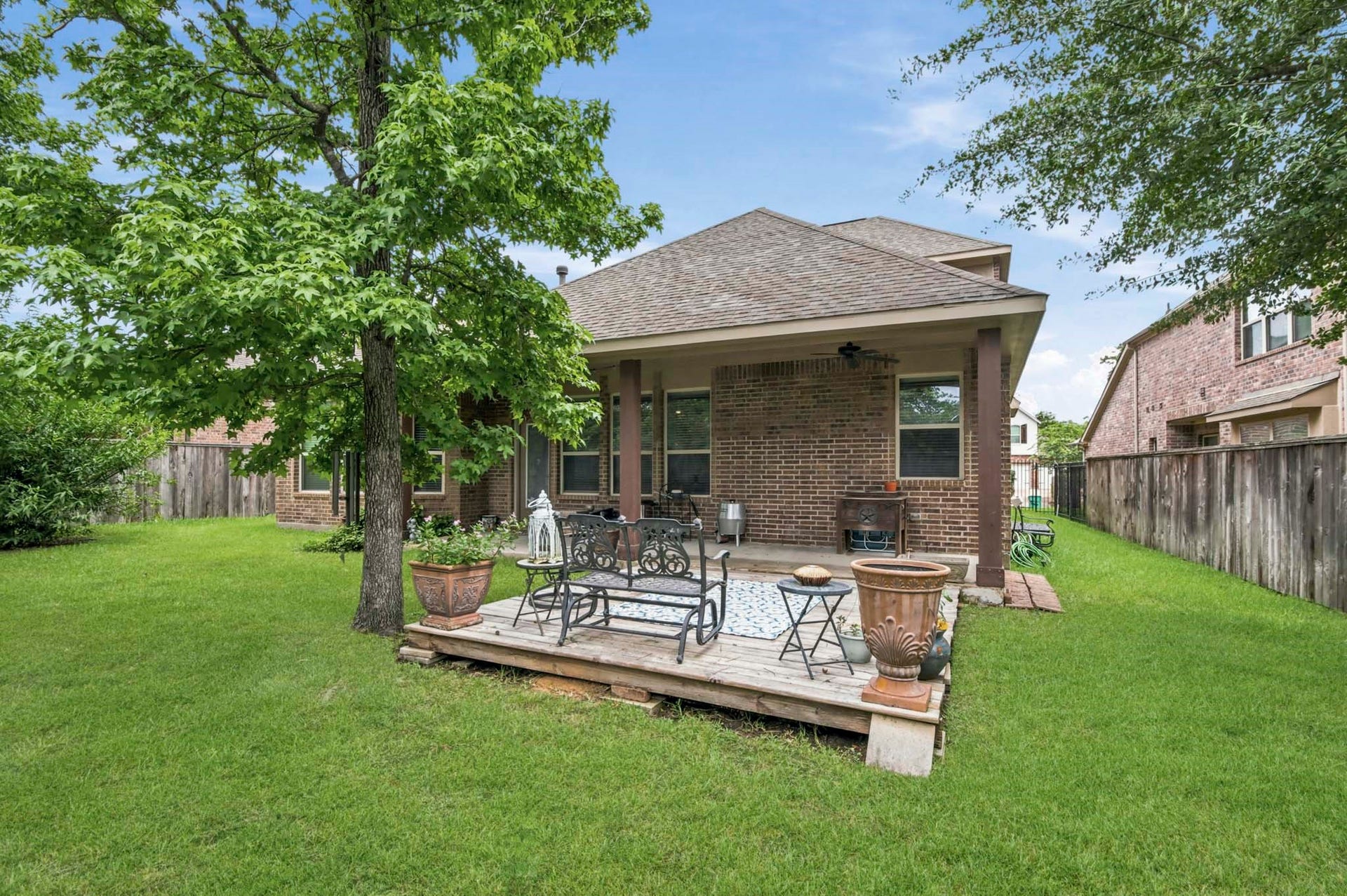 11 Whispering Thicket Place, The Woodlands, TX 77375 Backyard retreat featuring a covered patio, perfect for outdoor relaxation and entertaining, set against a backdrop of lush greenery.