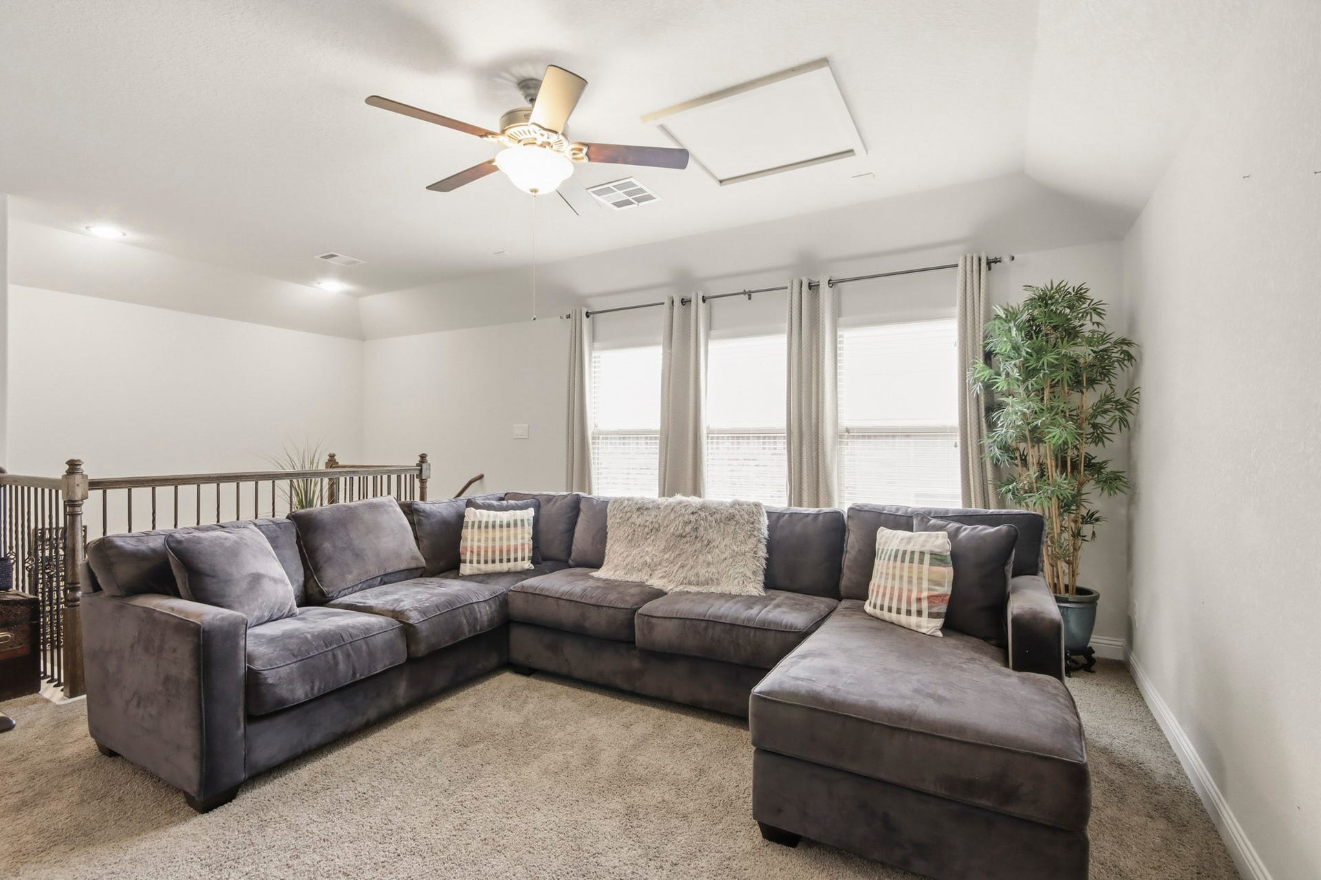 11 Whispering Thicket Place, The Woodlands, TX 77375 Spacious and inviting upstairs game room featuring soft carpeting, large windows that fill the space with natural light, and a ceiling fan for added comfort