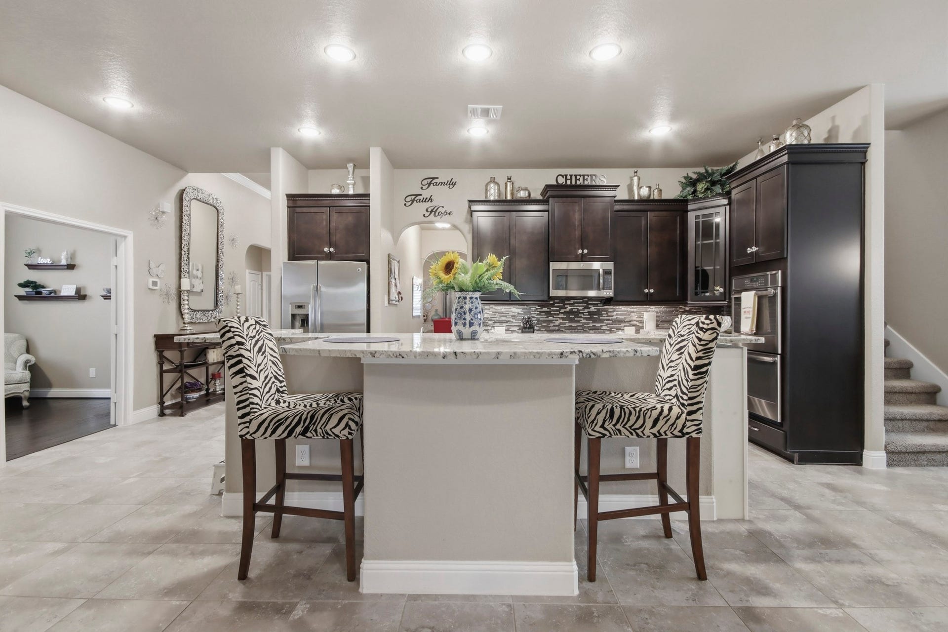 11 Whispering Thicket Place, The Woodlands, TX 77375 Gourmet kitchen featuring dark wood cabinets, a sleek stainless steel fridge, and a stylish island perfect for entertaining.