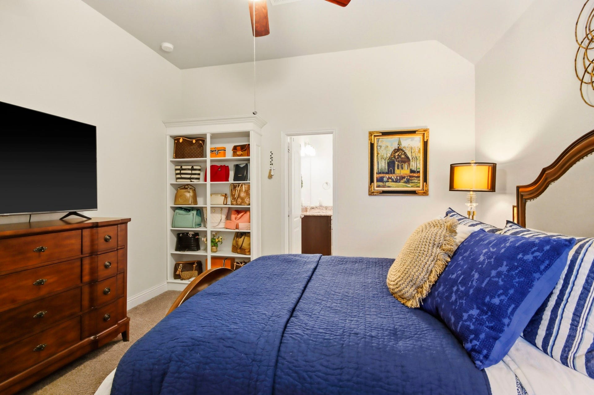 11 Whispering Thicket Place, The Woodlands, TX 77375 Another view of the secondary bedroom featuring built-in shelving, a ceiling fan, and convenient access to an ensuite bathroom.