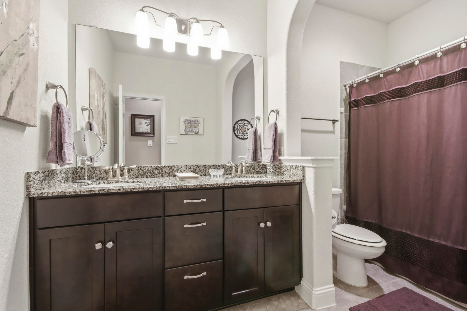 11 Whispering Thicket Place, The Woodlands, TX 77375 Hallway bathroom featuring a granite countertop with dual sinks and stylish dark cabinetry.