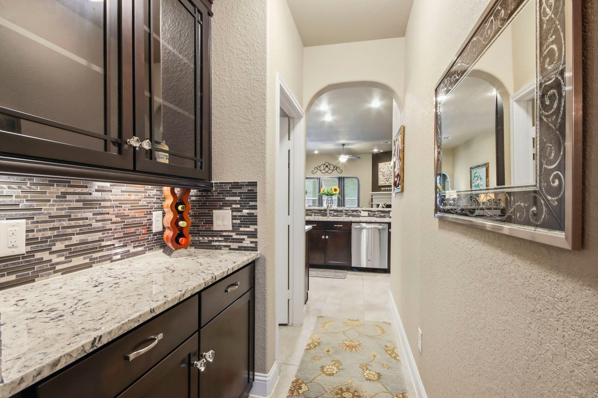 11 Whispering Thicket Place, The Woodlands, TX 77375 Butler's Pantry with custom cabinetry and a granite countertop, leading to a spacious kitchen with stainless steel appliances.