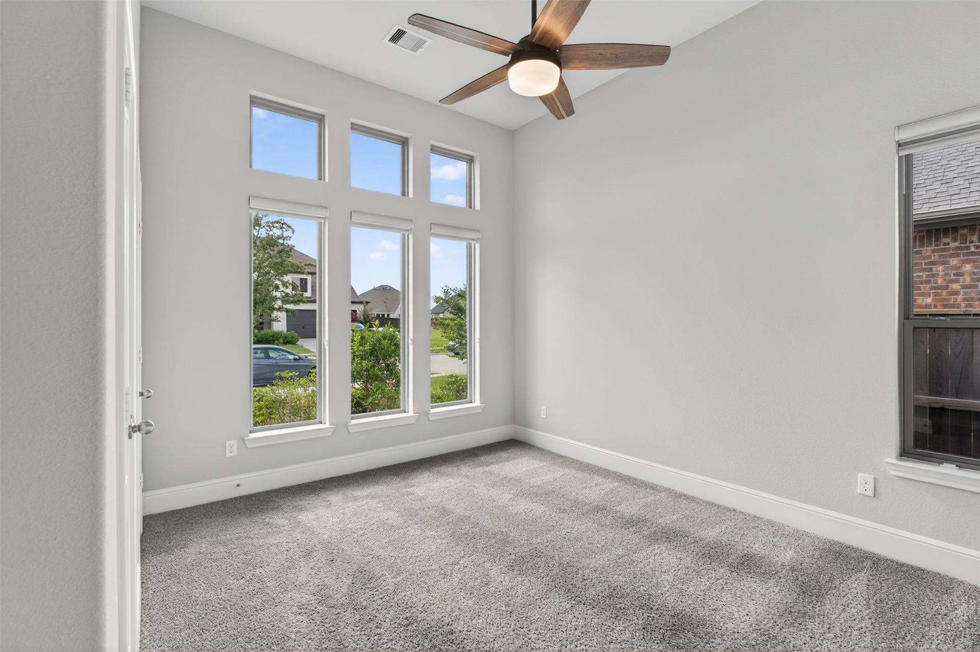3123 Lantana Trail, Katy, TX 77493 The secondary bedroom on the main floor offers a bright and welcoming retreat, enhanced by expansive floor-to-ceiling windows that fill the space with natural light.