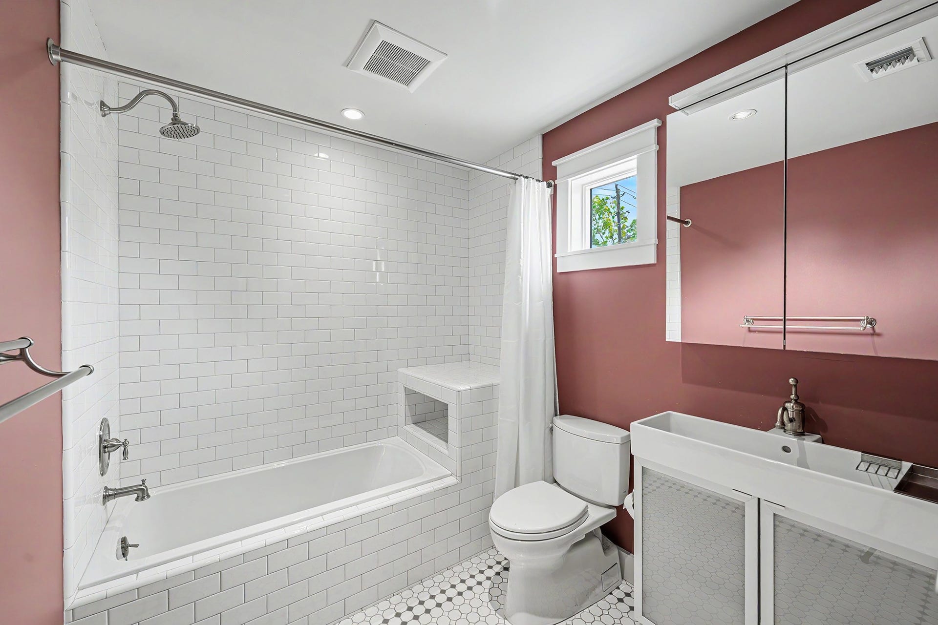 4153 Oberlin Street, West University Place, TX 77005 The attached bathroom features a tub/shower combo with a subway tile surround, penny tile flooring, and a modern vanity with sink, combining classic style with contemporary finishes.