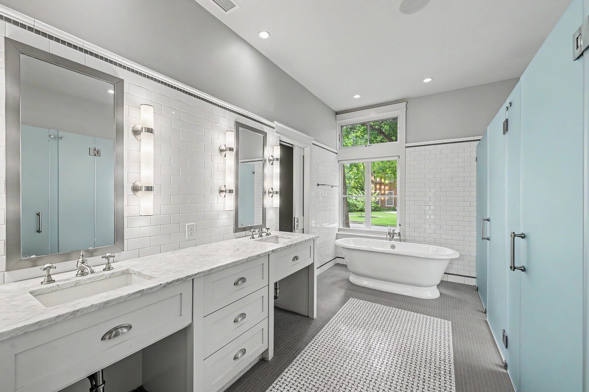 4153 Oberlin Street, West University Place, TX 77005 The primary bath showcases timeless design with a spacious walk-in shower, dual vanities, separate water closets, and a soaking tub. Carrara marble countertops and flooring with a marble basket-weave tile insert complete the space, finished with classic, neutral fixtures and finishes.