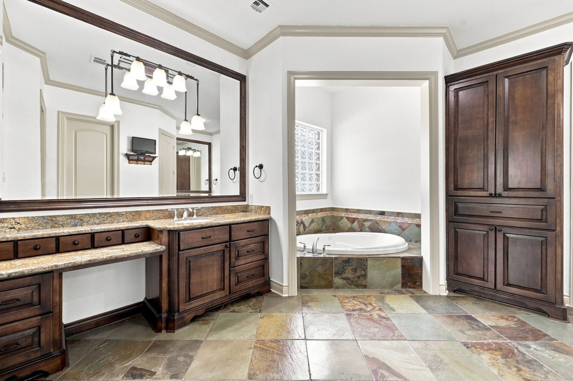5411 Woodbury Street, Fulshear, TX 77441 The luxurious Primary Bathroom offers custom cabinetry, gorgeous slate flooring, and elegant double vanities, creating a sophisticated and relaxing retreat.