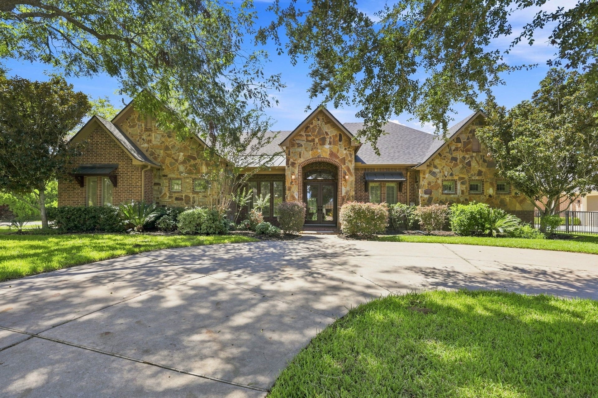 5411 Woodbury Street, Fulshear, TX 77441 Beautifully positioned on a gorgeous wooded half-Acre lot overlooking the 2nd tee box of the golf course. A circular driveway creates an impressive arrival, while the striking exterior showcases authentic stone, tumbled brick, and a distinctive gable roof design. Mature trees surround the property, creating a peaceful, private setting and a beautiful connection to the natural landscape.