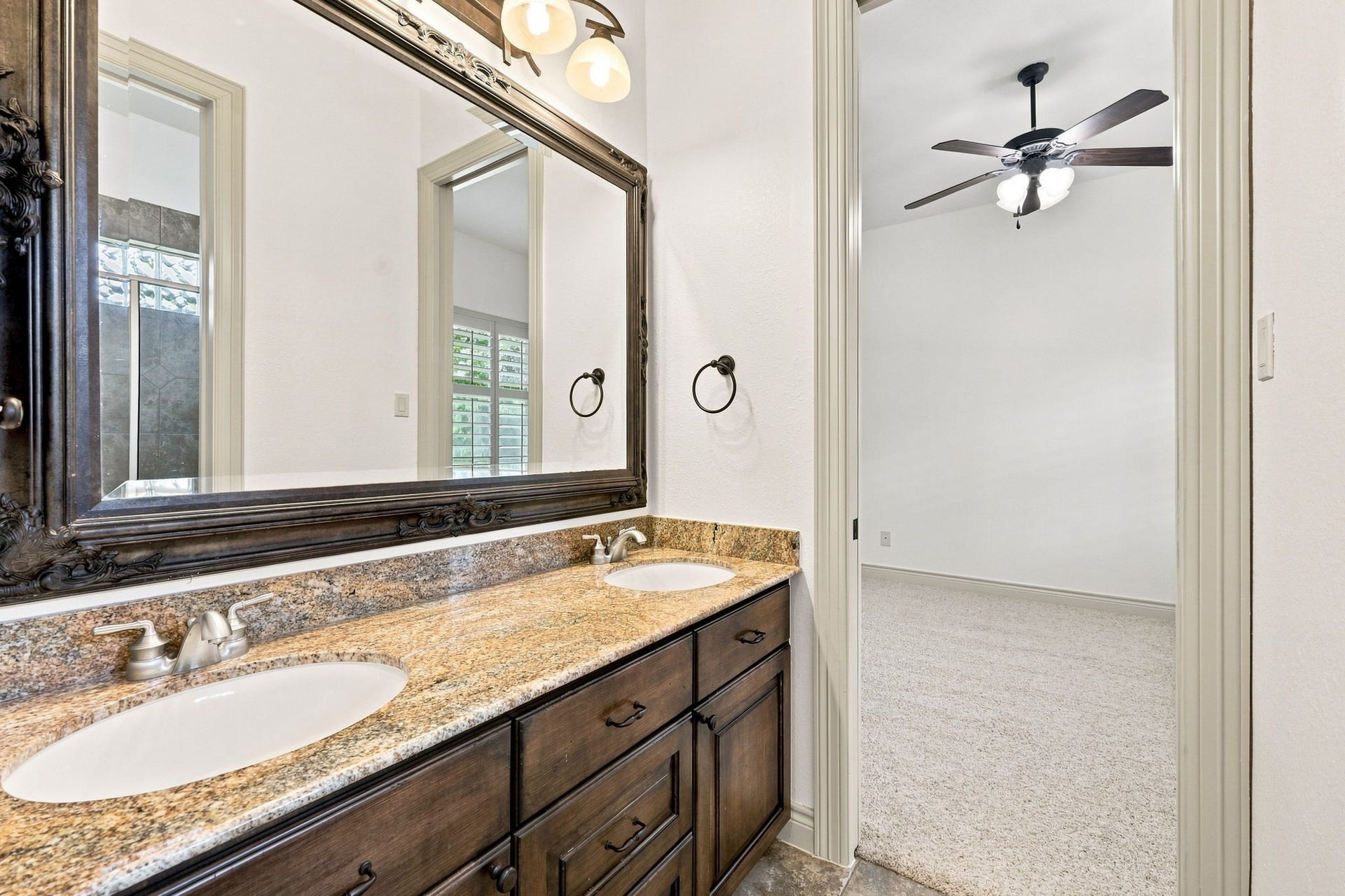 5411 Woodbury Street, Fulshear, TX 77441 This beautifully appointed Full Bath serves two of the secondary bedrooms and features dual sinks, custom cabinetry, and an elegant framed mirror. Oil-rubbed bronze light fixtures add a sophisticated finishing touch to this stylish and functional bathroom.