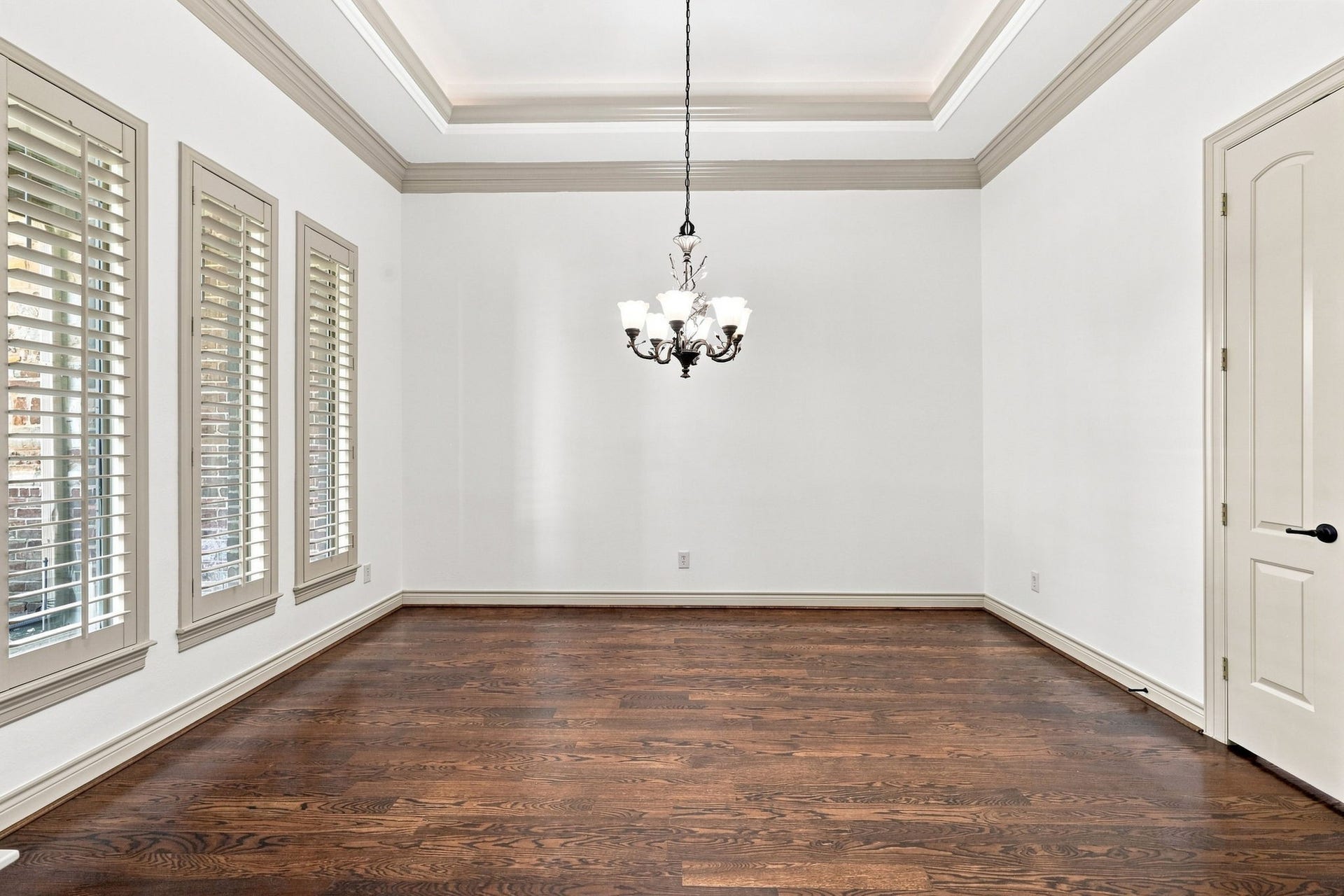5411 Woodbury Street, Fulshear, TX 77441 The elegant Formal Dining room is perfectly suited for holiday celebrations and memorable family gatherings. A beautiful designer paint color complements the space, while three windows with Plantation Shutters provide an abundance of natural light and timeless appeal. The raised ceiling adds volume and architectural interest, beautifully accented by a sophisticated oil-rubbed bronze chandelier.