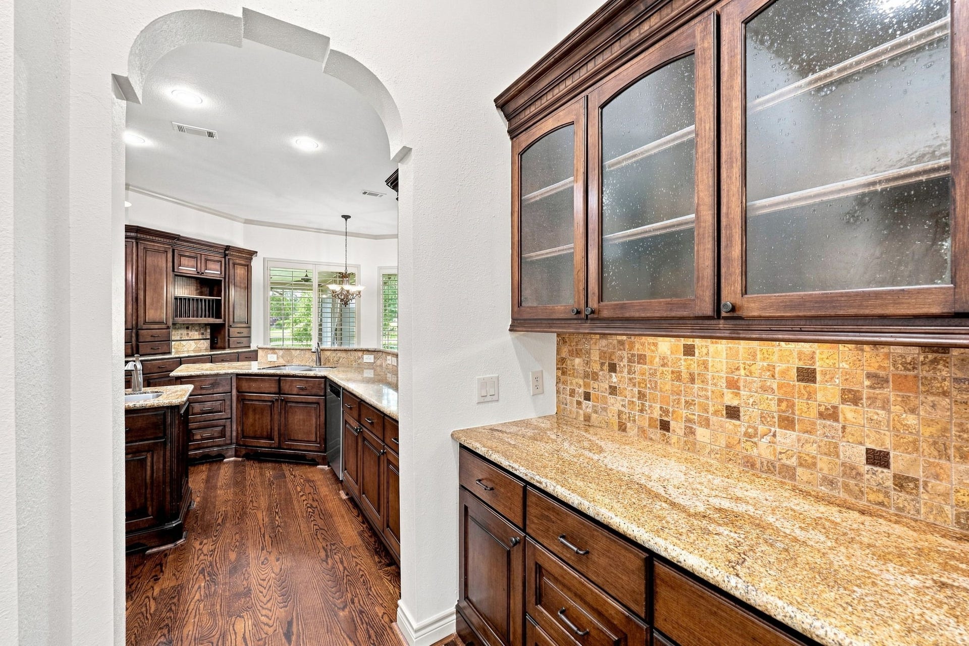 5411 Woodbury Street, Fulshear, TX 77441 The elegant Butlers Pantry conveniently connects the Formal Dining and Kitchen areas, making entertaining effortless. Beautiful glass-front cabinetry provides a stylish way to display favorite dishes and serving pieces, while gorgeous granite countertops and abundant storage offer plenty of space for dinnerware, glassware, and entertaining essentials.