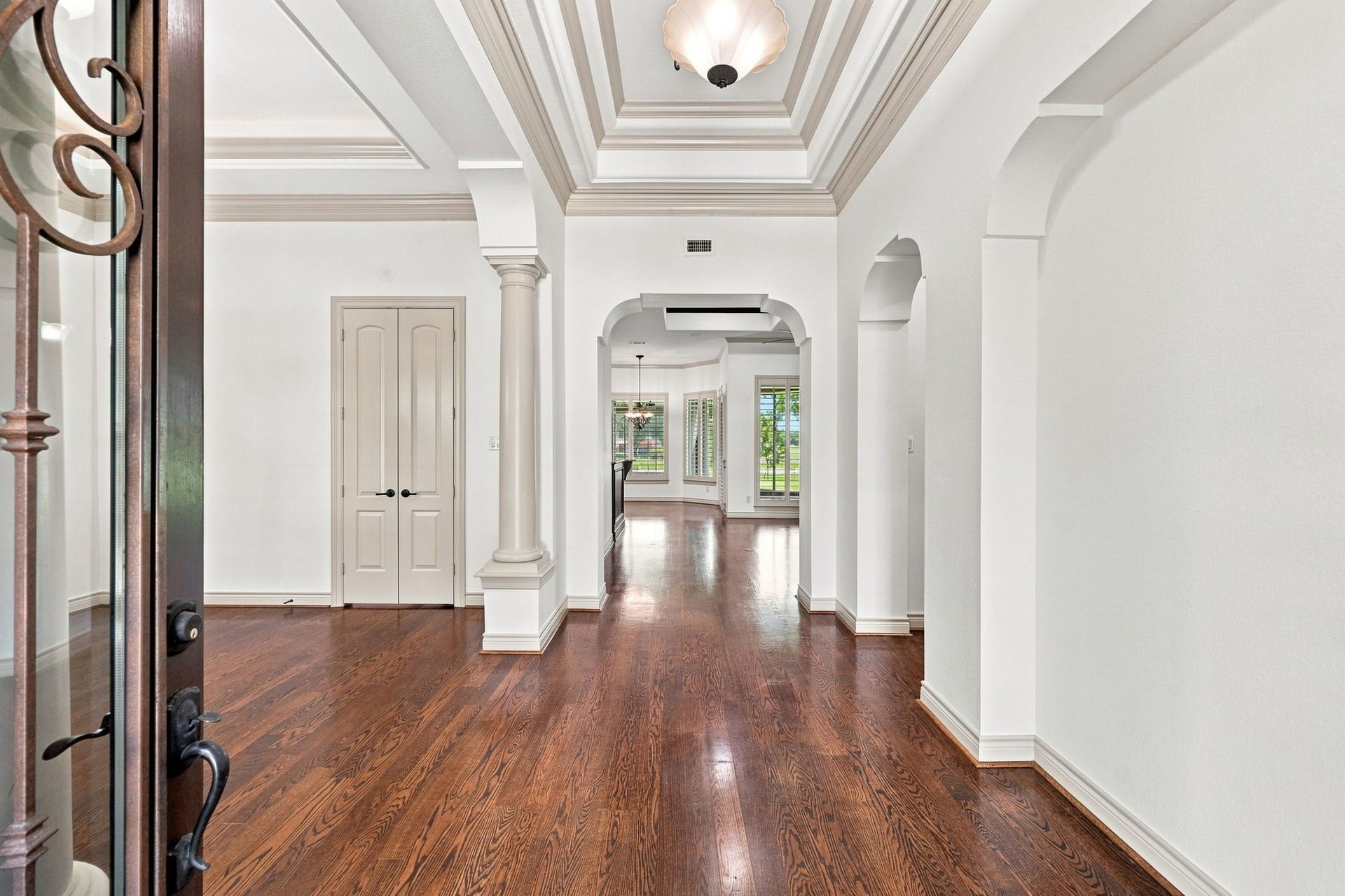5411 Woodbury Street, Fulshear, TX 77441 As you enter through the impressive double iron doors, you are greeted by gorgeous wood floors, freshly painted light-toned interiors, and an elegant foyer designed to make a lasting impression. A dramatic raised ceiling with detailed crown molding adds architectural character and creates a grand sense of arrival.