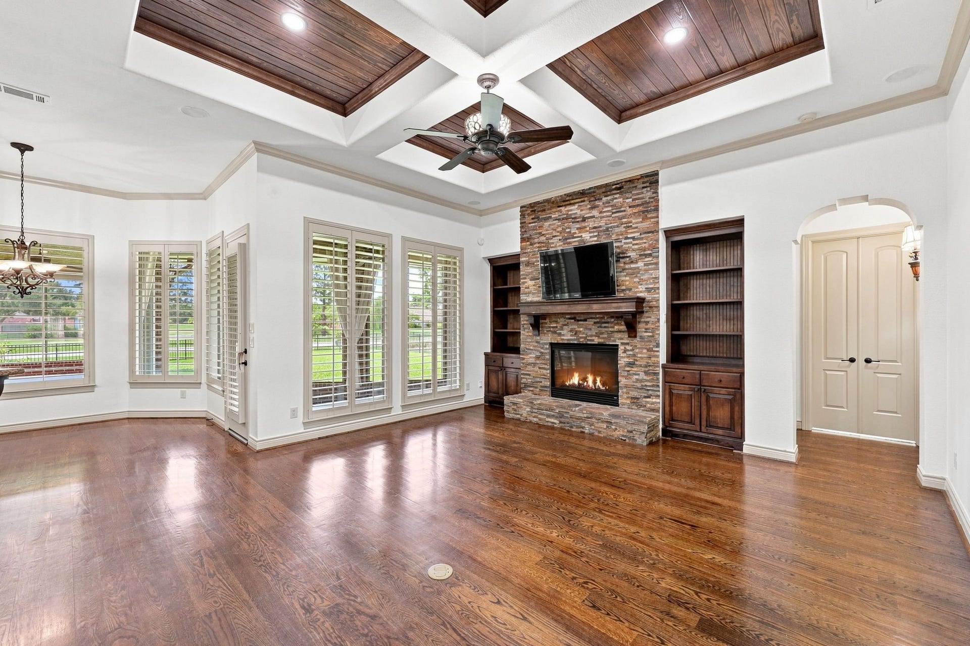 5411 Woodbury Street, Fulshear, TX 77441 The spectacular Family Room is designed for both elegant entertaining and comfortable everyday living. A beautifully crafted wood coffered ceiling adds warmth and architectural distinction, while an impressive gas-log Fireplace is framed by a striking stacked-stone surround and custom built-in shelving on either side. Rich wood floors extend throughout the space, while numerous windows with Plantation Shutters fill the room with natural light and offer picturesque views of the gorgeous backyard.