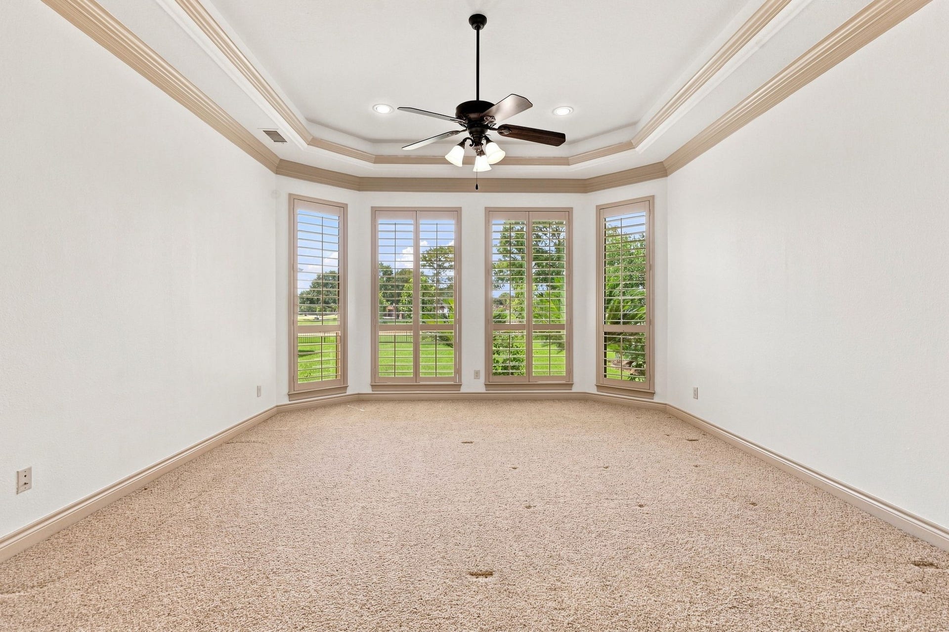 5411 Woodbury Street, Fulshear, TX 77441 The expansive Primary Bedroom offers a luxurious and serene retreat, featuring lush wall-to-wall carpeting and a dramatic raised ceiling accented by elegant crown molding. Four large windows with Plantation Shutters fill the room with natural light while providing beautiful views of the gorgeous backyard.