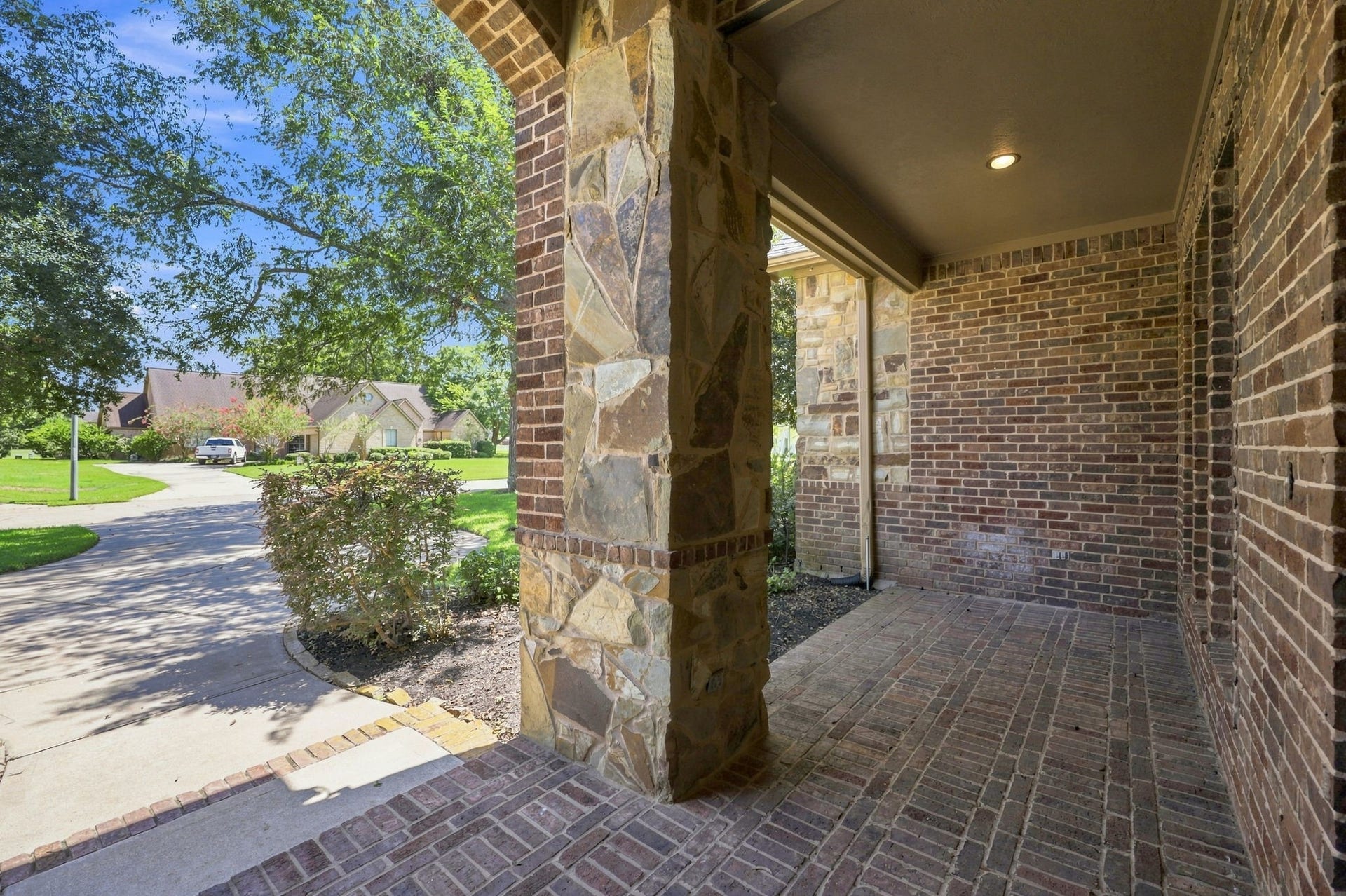 5411 Woodbury Street, Fulshear, TX 77441 As guests make their way to the front entrance, they are welcomed by an expansive covered front porch featuring beautiful brick flooring and impressive stone and brick columns. This inviting entry creates a grand first impression while complementing the homes distinctive architectural design.