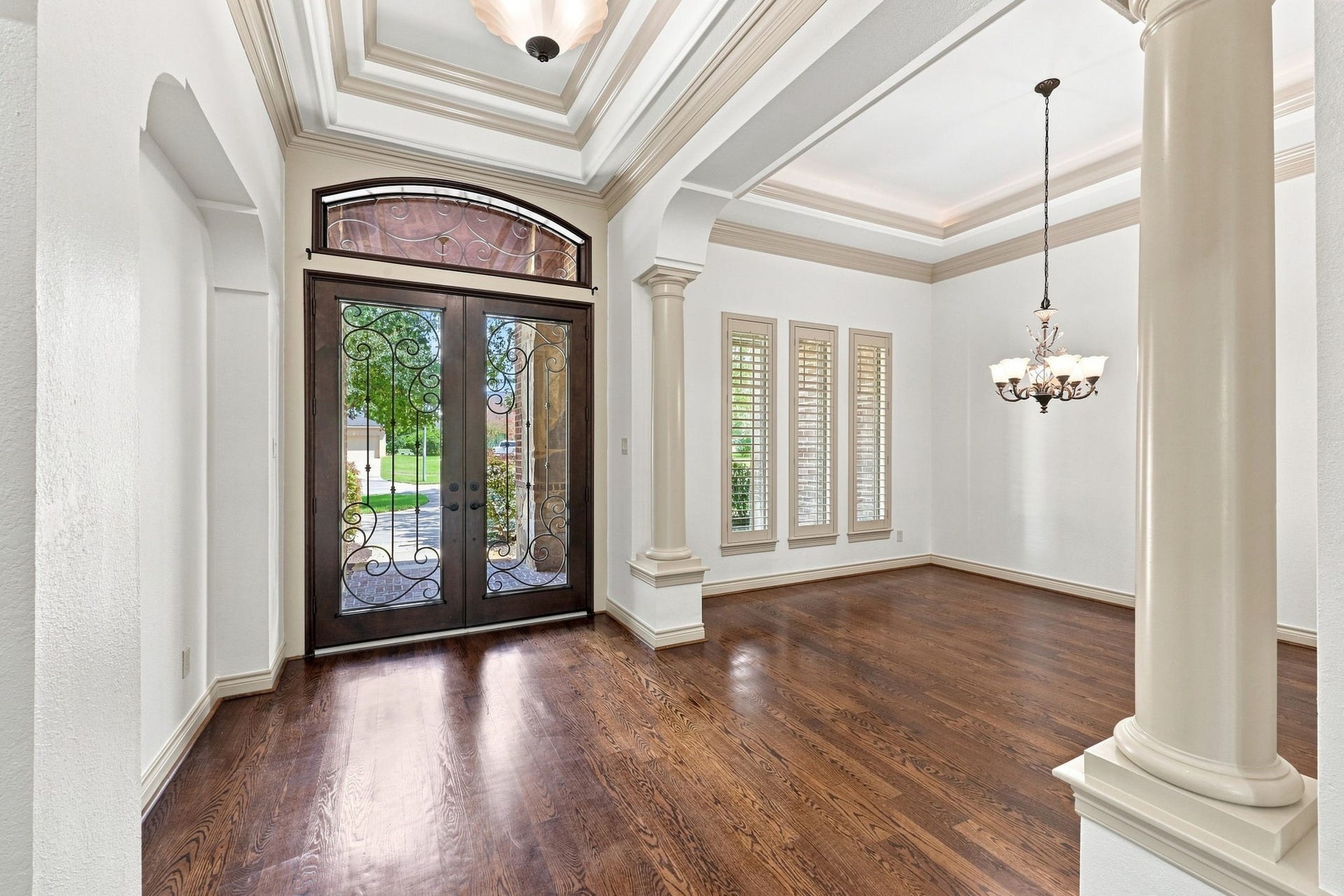 5411 Woodbury Street, Fulshear, TX 77441 Looking back toward the front entrance, this view showcases the impressive double iron doors, accented by an elegant transom window above that allows an abundance of natural light to fill the foyer. The striking doors and light-filled entry create a beautiful first impression and complement the homes sophisticated architectural details.