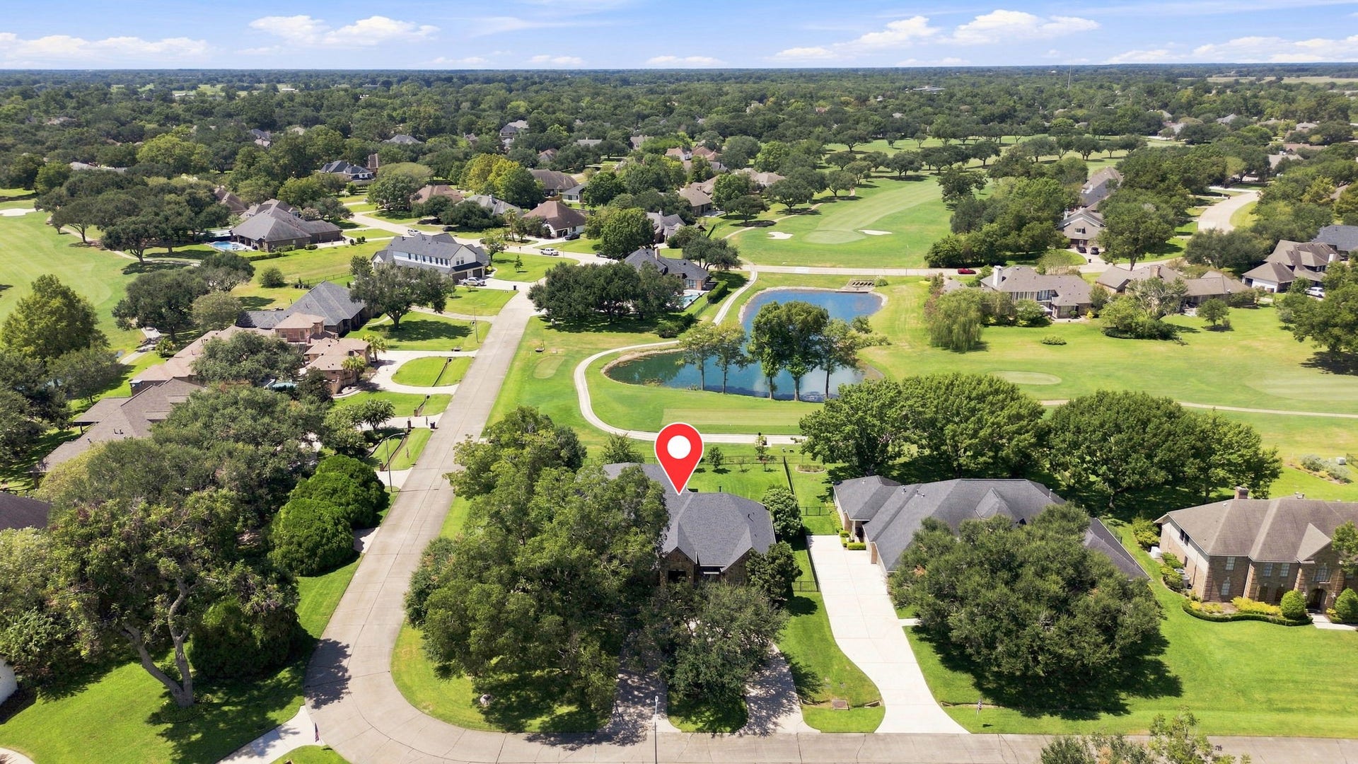 5411 Woodbury Street, Fulshear, TX 77441 Welcome to 5411 Woodbury Street. with an exceptional golf course setting, with the home pinpointed for easy viewing. The photo showcases the beautiful golf course backdrop, tranquil pond, and mature wooded surroundings that make this half-Acre homesite truly special.