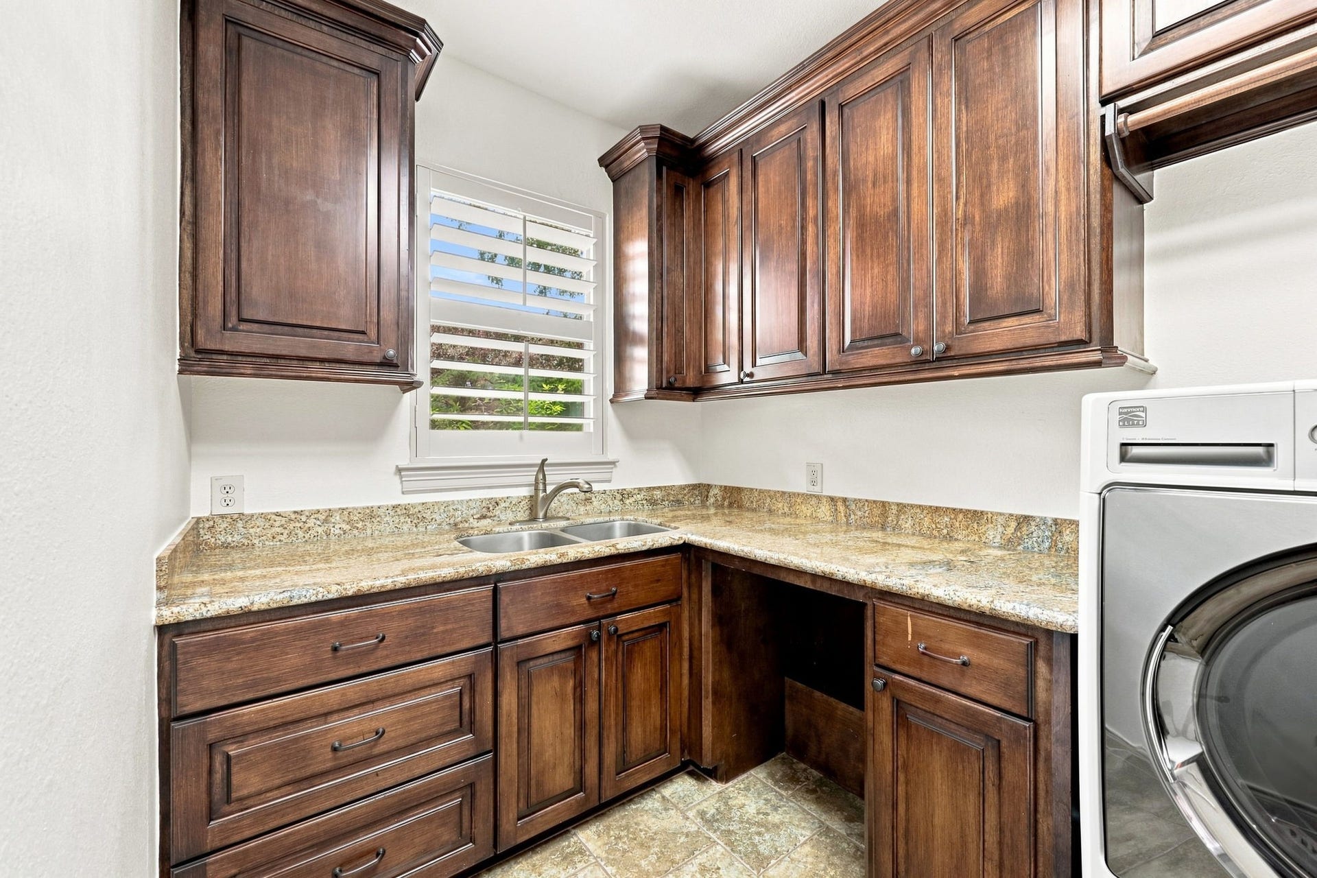 5411 Woodbury Street, Fulshear, TX 77441 The oversized Laundry Room is both beautiful and highly functional, featuring lots of custom cabinetry, gorgeous granite countertops with generous space for folding clothes, and a convenient stainless-steel sink. Thoughtfully designed for everyday efficiency, this spacious laundry room offers exceptional storage and workspace.