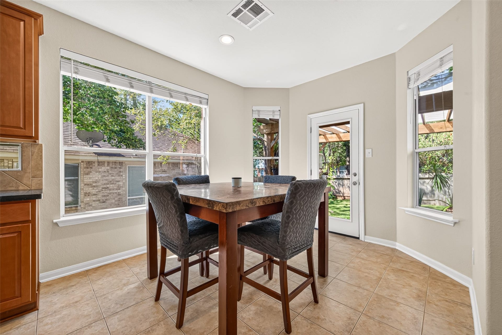 Bright and inviting breakfast area featuring large windows, tile flooring, and easy access to the backyard through a glass door. Perfect for casual dining with a view!