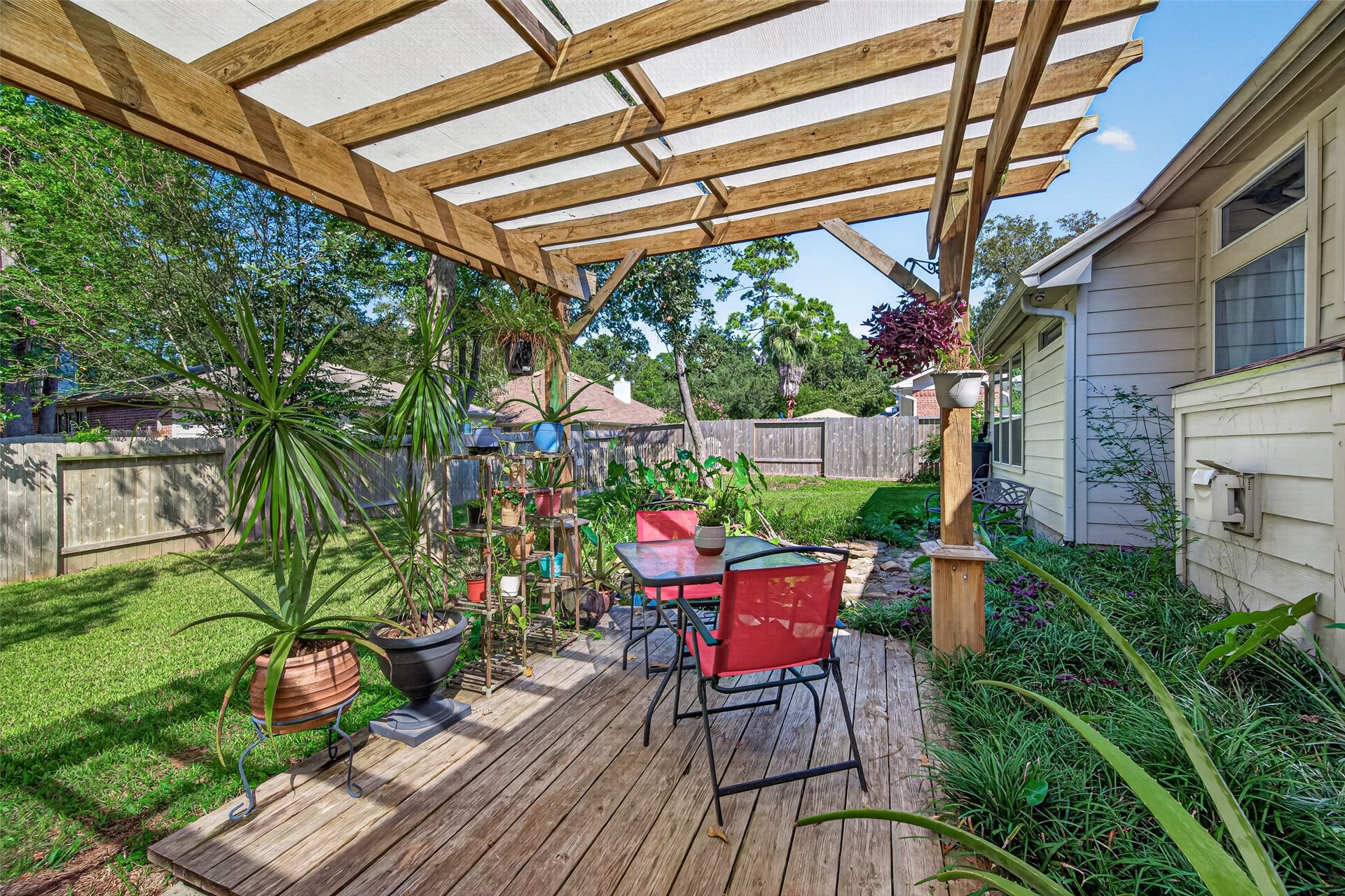 Closer view of the charming pergola-covered deck, surrounded by greenery and garden accents.