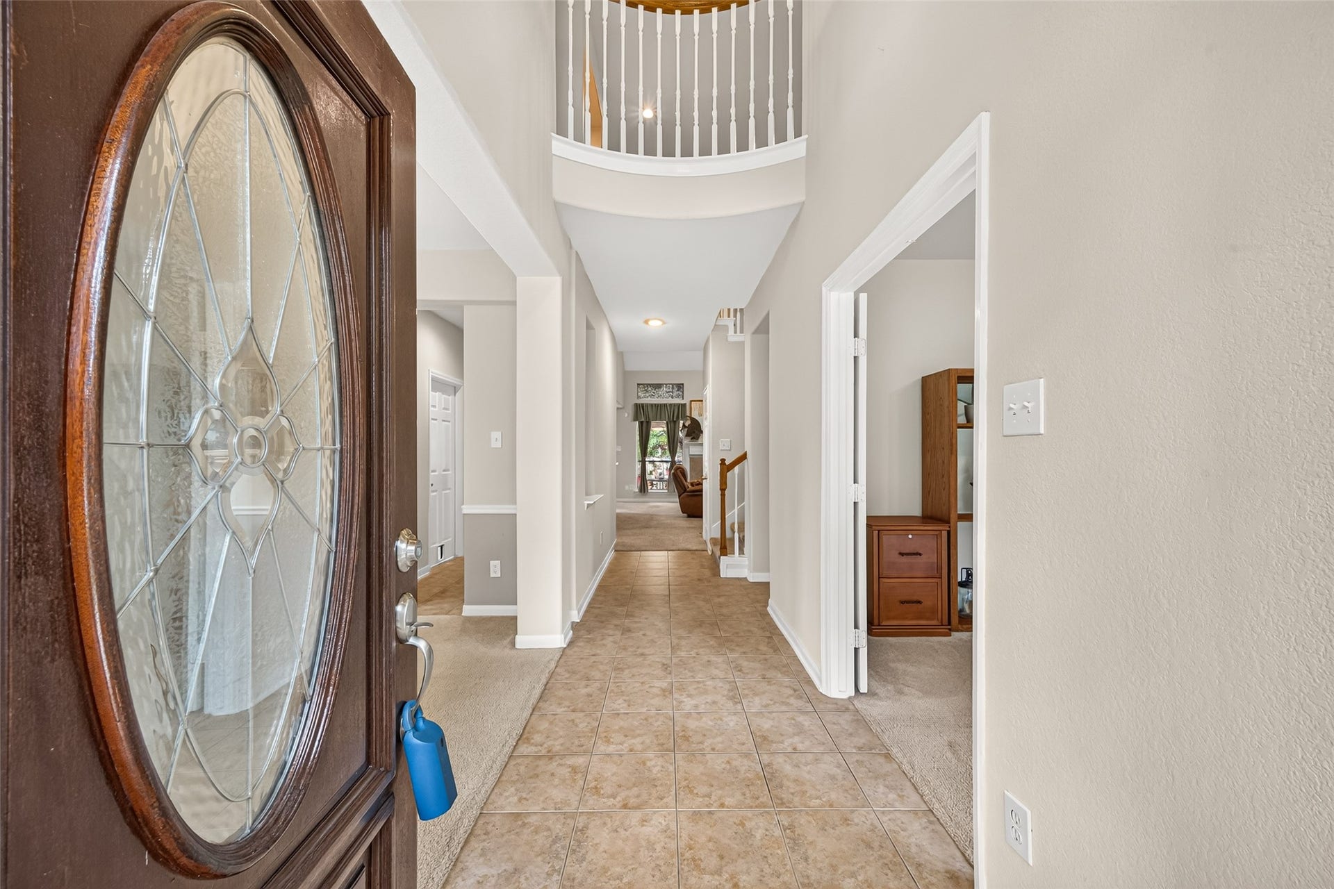 Step inside to a welcoming two-story foyer featuring tile flooring, soaring ceilings, and an open view toward the main living area.