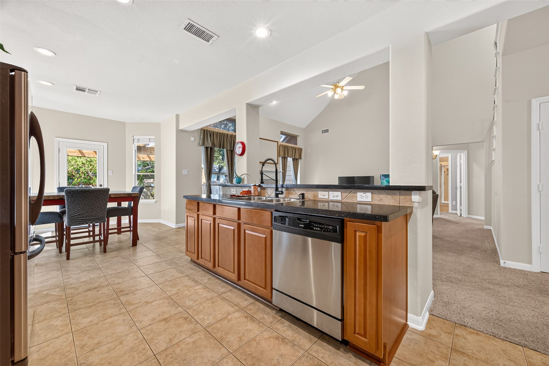 Open-concept kitchen with a breakfast bar, stainless steel dishwasher, and views into the spacious living roomideal for everyday living and entertaining.