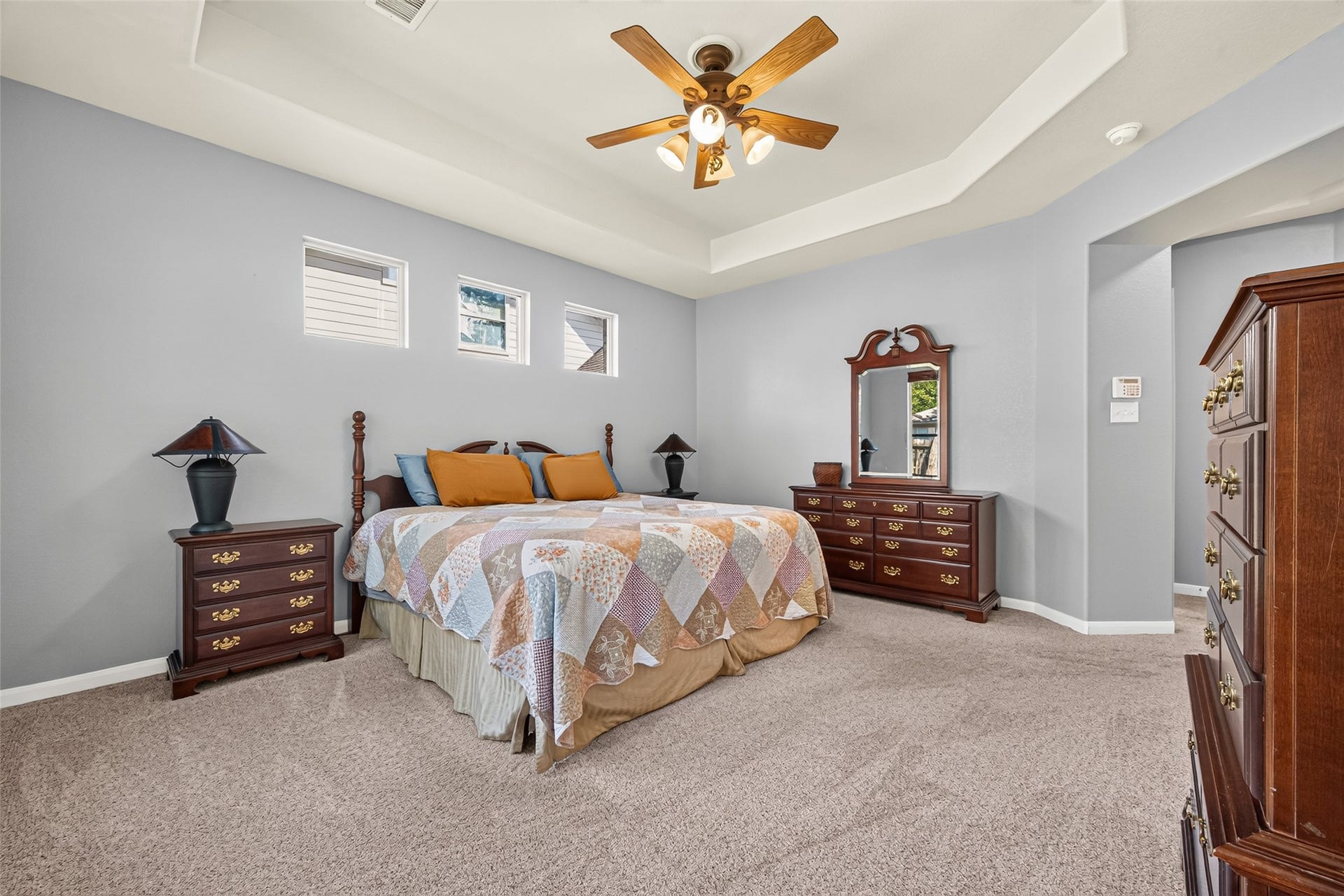 The generously sized primary bedroom offers plenty of room for furnishings, complemented by a decorative tray ceiling and ceiling fan.