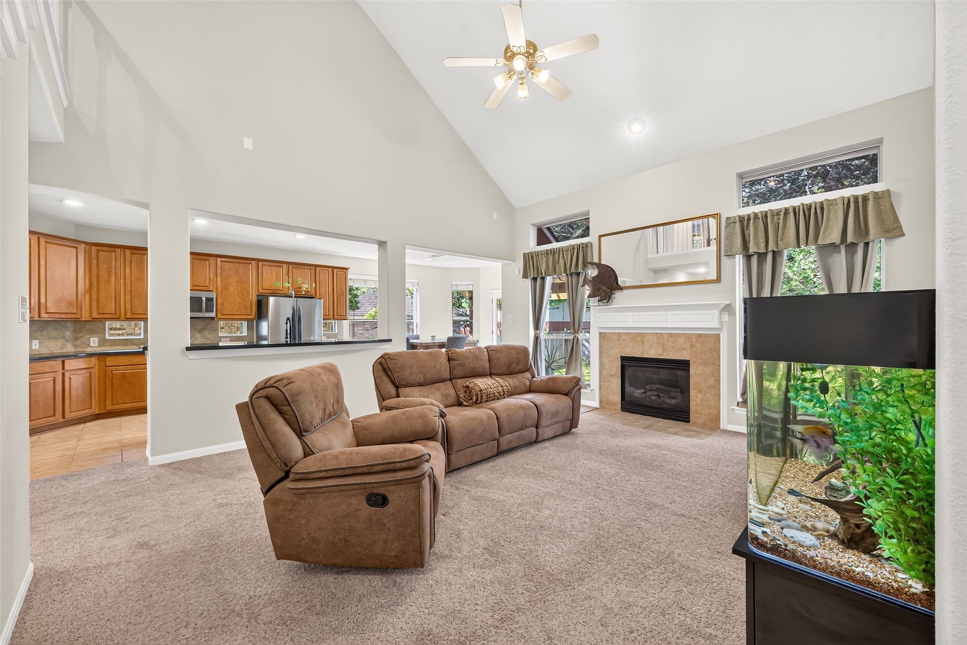 Another inviting view of the living room showcasing the fireplace, expansive windows, and convenient kitchen pass-through, ideal for everyday living and entertaining.