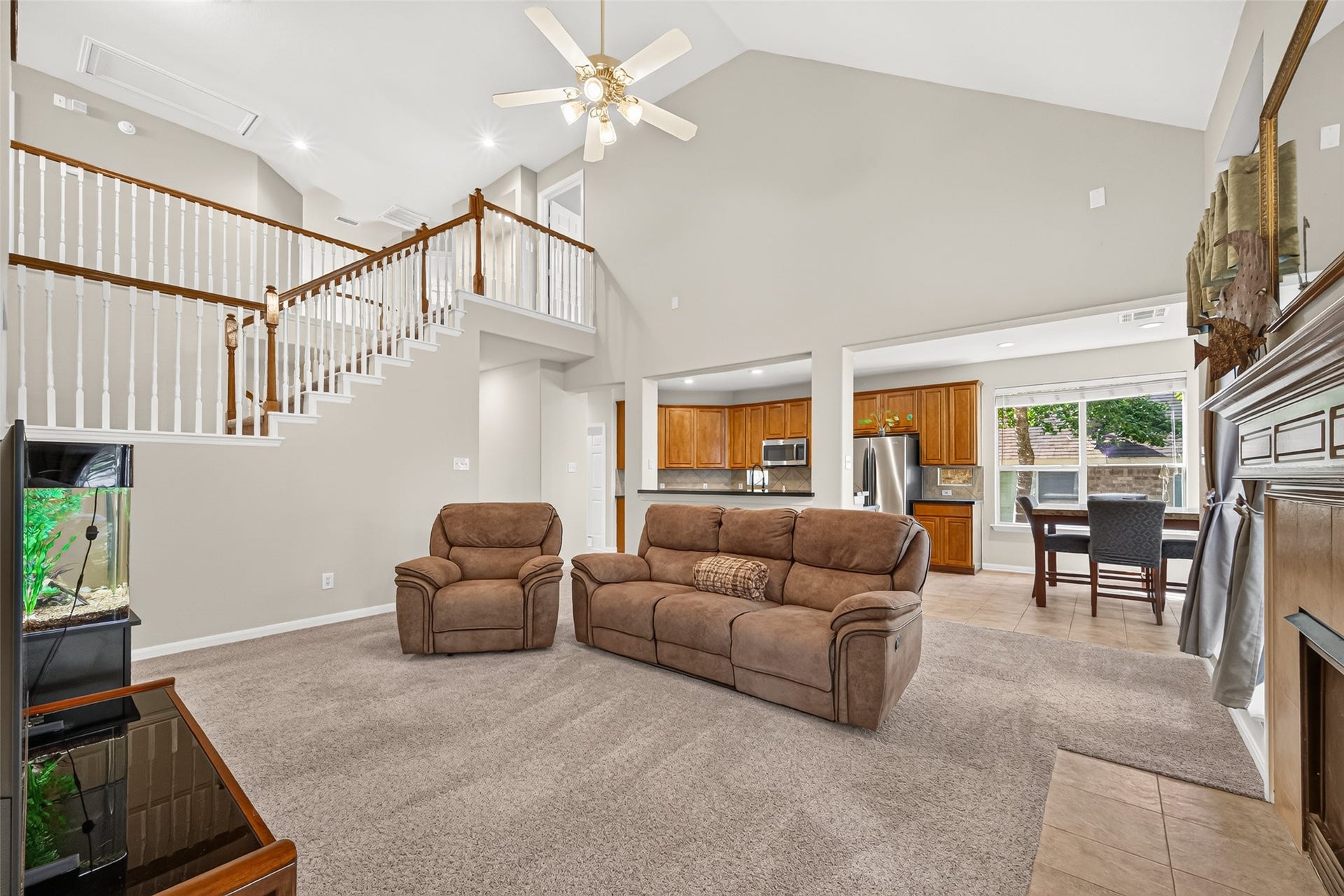 Impressive open-concept living area with soaring ceilings, a second-floor overlook, and seamless flow into the kitchen and breakfast area.