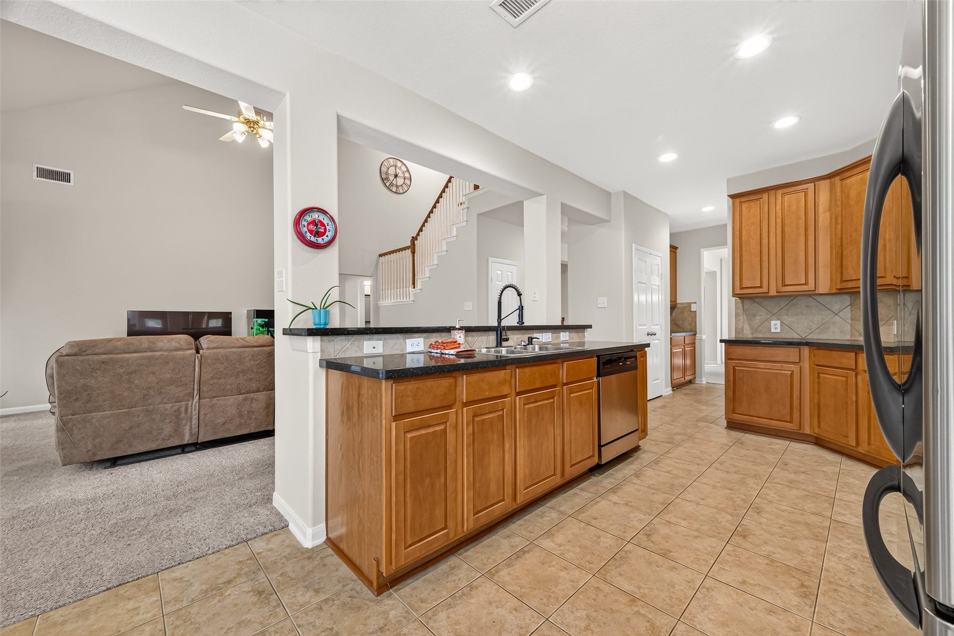 Another view of the kitchen highlighting the breakfast bar, ample cabinetry, and seamless flow into the living area.