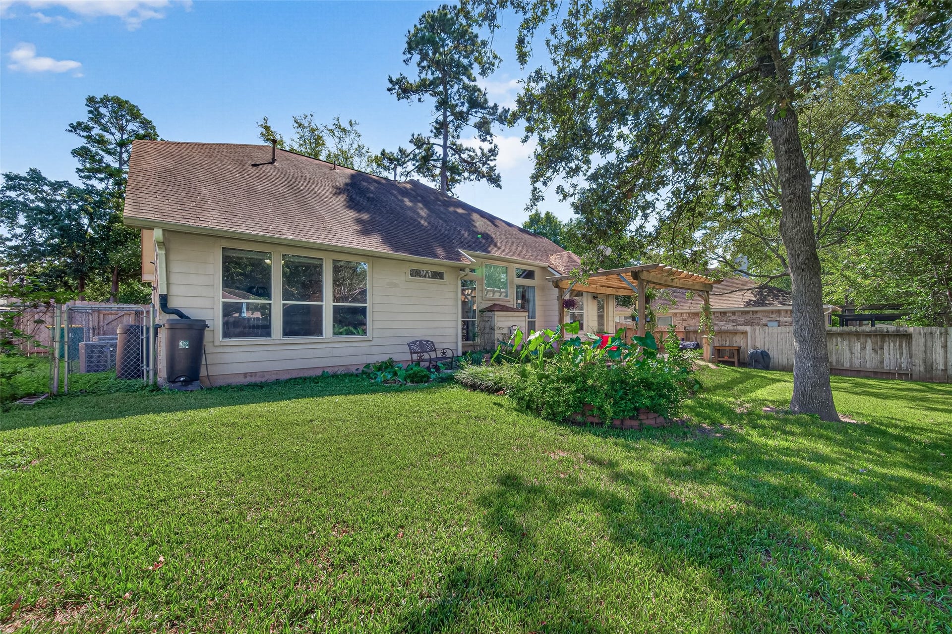 Rear exterior view highlighting the backyard lawn, mature trees, and established landscaping.