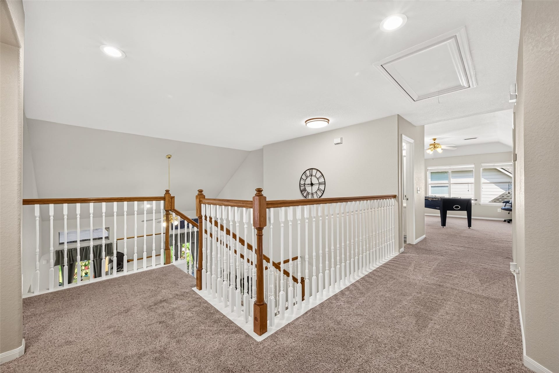 Spacious upstairs landing overlooking the entryway, featuring attractive wood railings and easy access to the upstairs game room and additional bedrooms.
