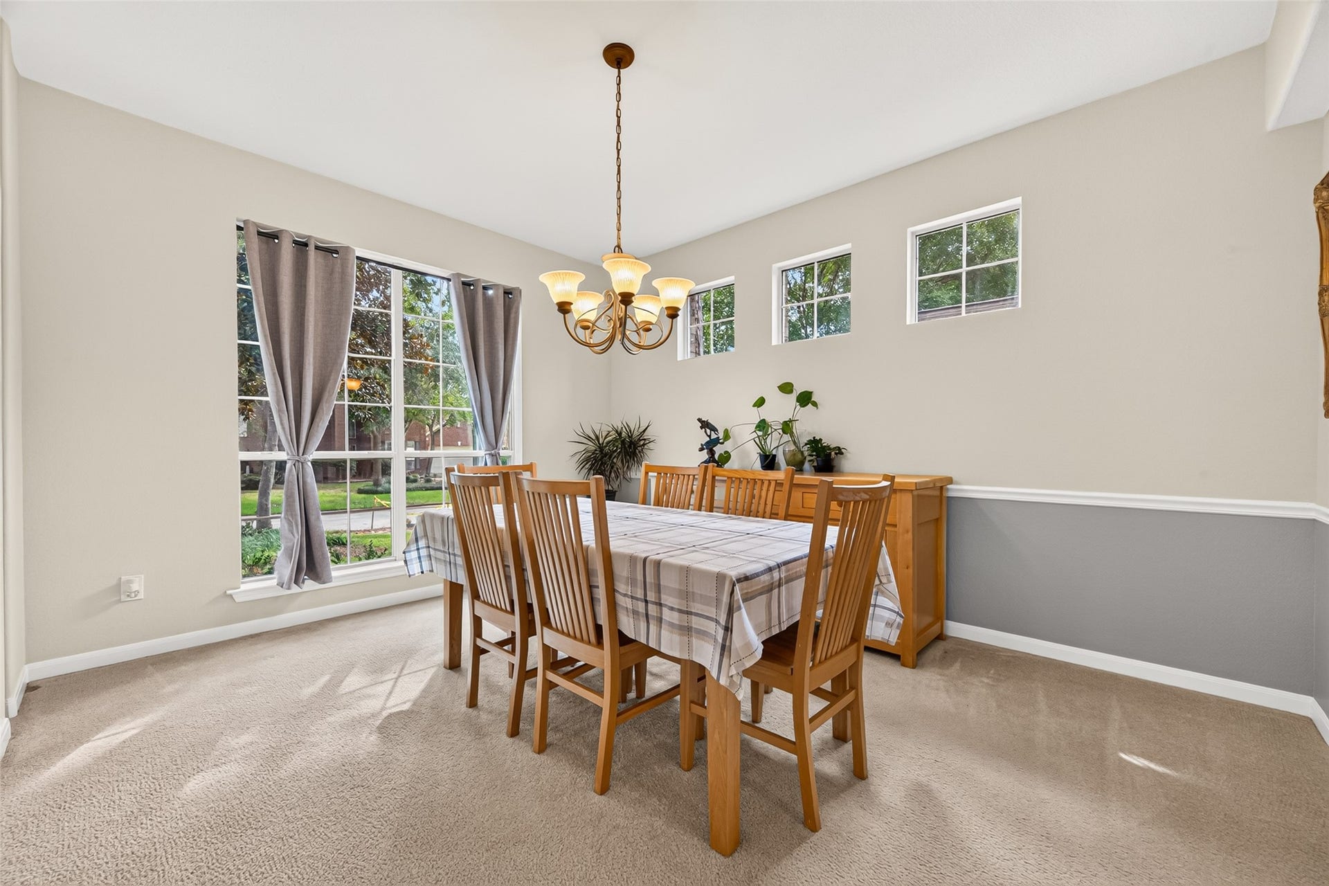 Spacious formal dining room featuring a beautiful chandelier, chair rail detailing, and large windows that fill the space with natural light.