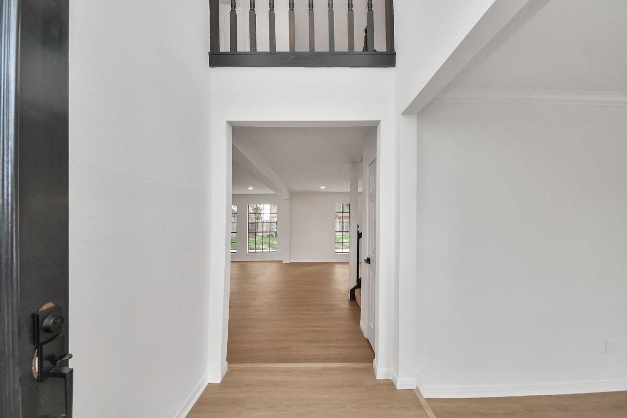 15047 Tramore Drive, Houston, TX 77083 Step inside and the story changes from traditional charm to fresh, modern living. Clean white walls, oversized baseboards, warm wood-look flooring, and an open sightline immediately create an airy sense of space.