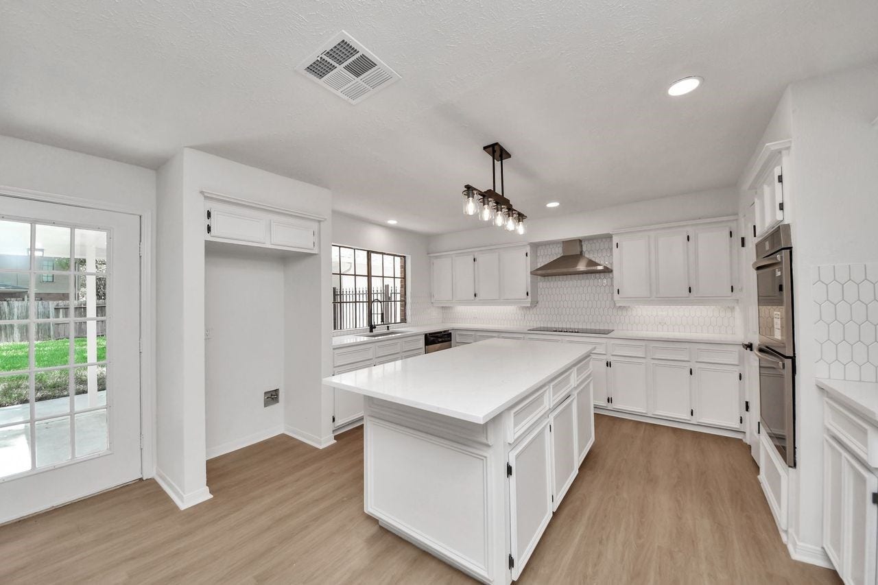 15047 Tramore Drive, Houston, TX 77083 This is where mornings begin. Natural light pours through the windows beside the breakfast area, creating a cheerful everyday gathering spot just steps from the beautifully updated kitchen. The kitchen is ready to be the center of it all. Crisp white cabinetry, a large island, sleek countertops, a striking tile backsplash, and stainless appliances create a bright, functional workspace with plenty of room to cook, gather, and entertain.